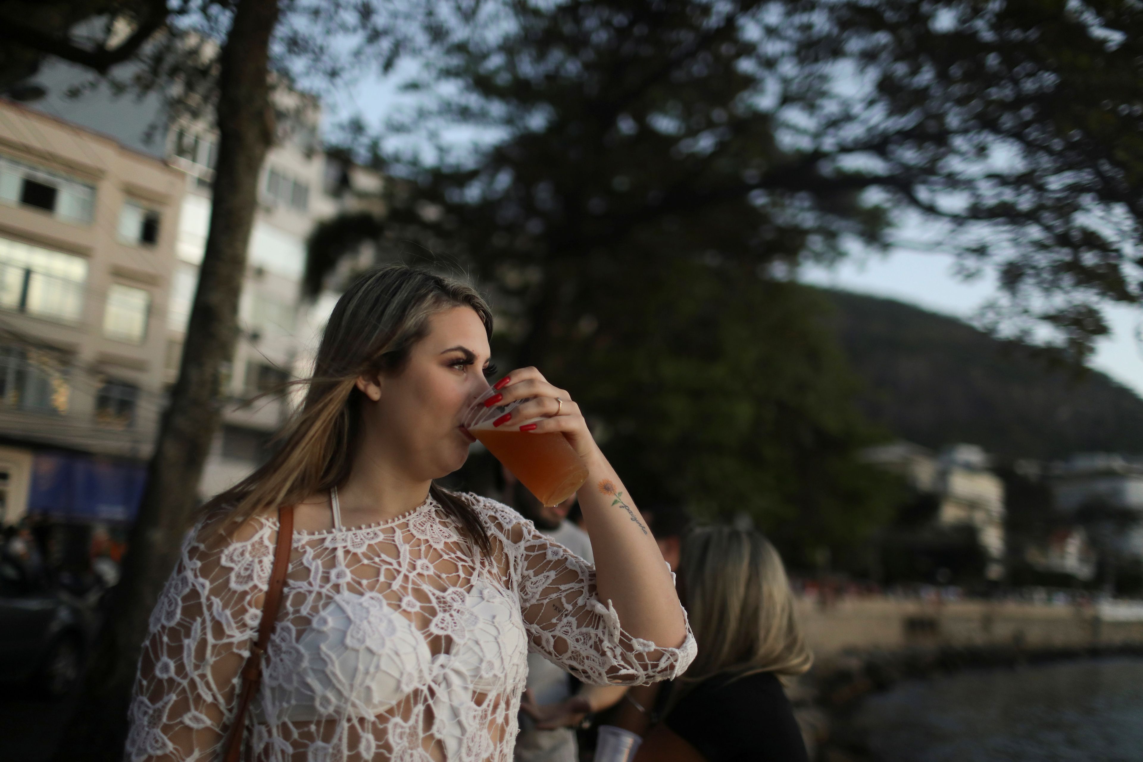 Una mujer bebe alcohol en la calle.