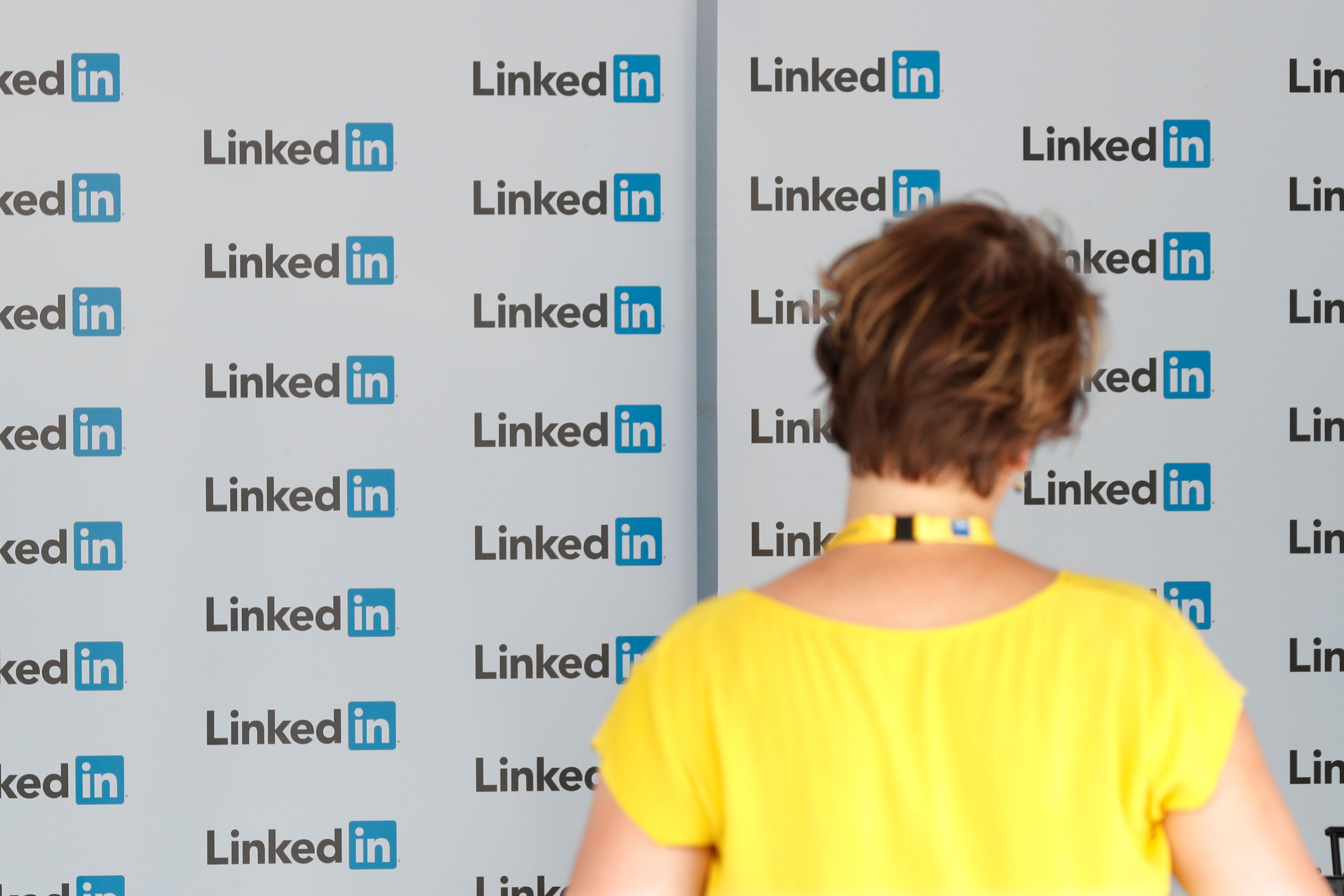 Una mujer delante de una pared con el logo de LinkedIn