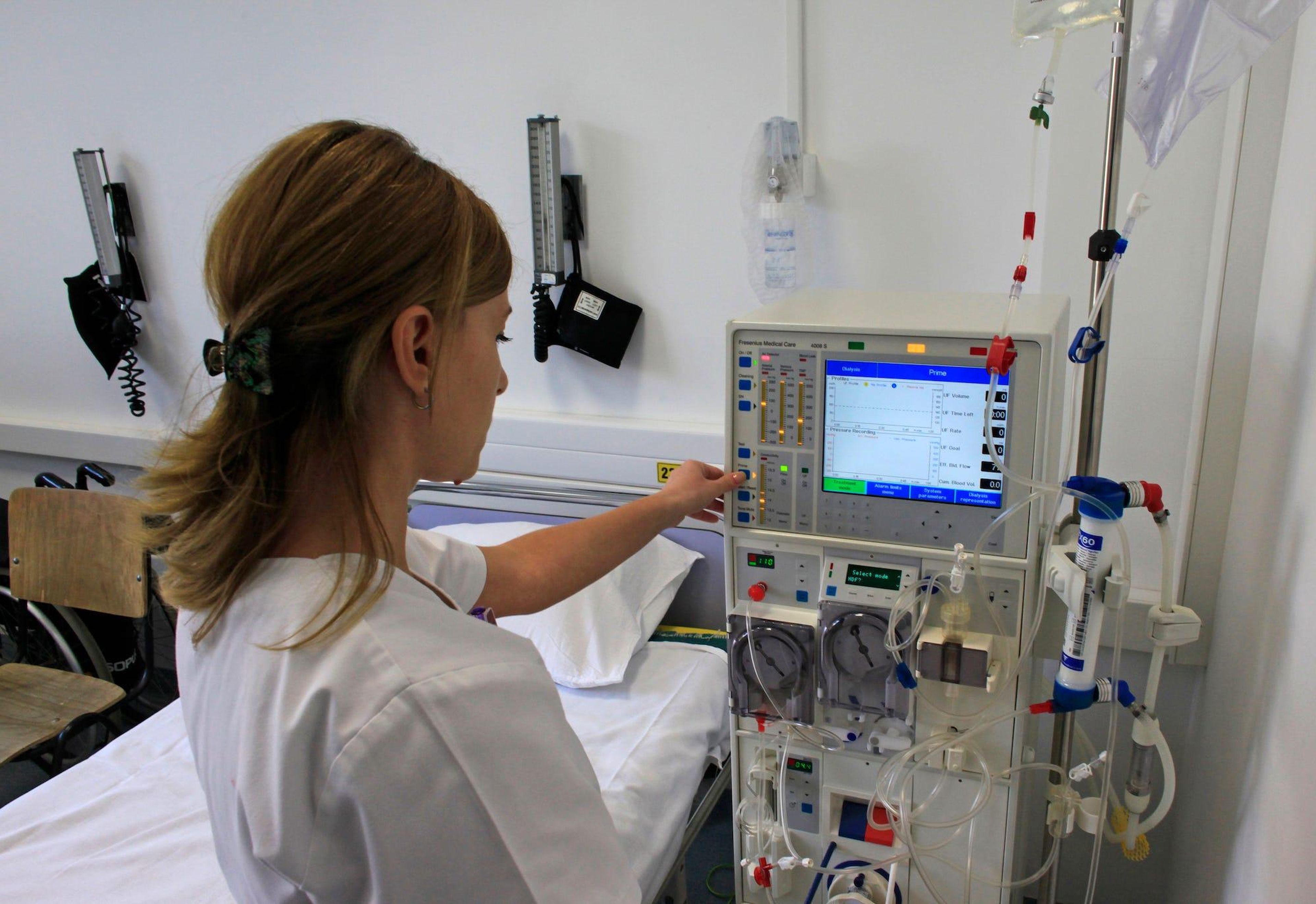 Una enfermera prepara una máquina de diálisis.