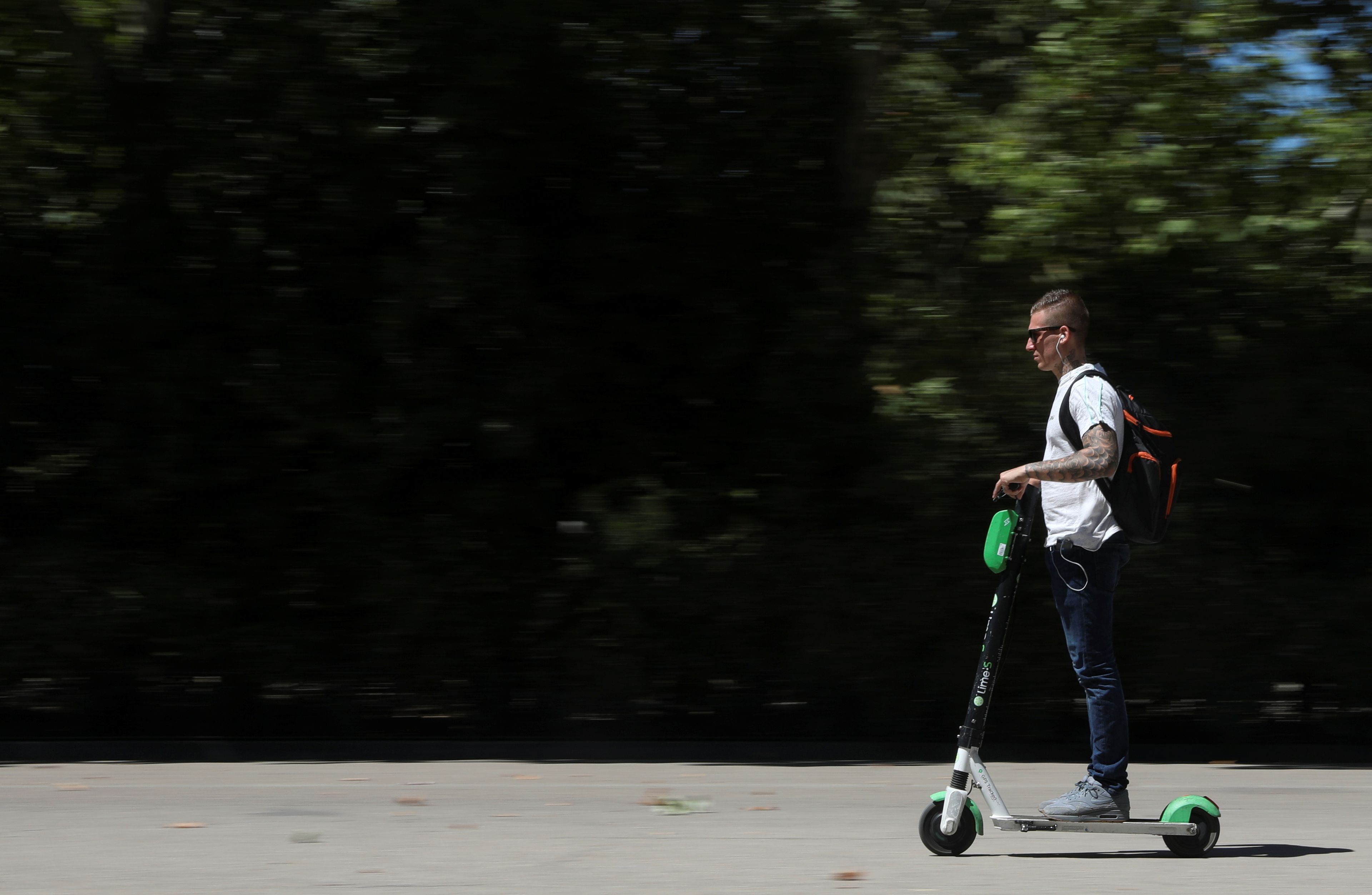 Un hombre utiliza un patinete eléctrico compartido de Lime, Madrid.