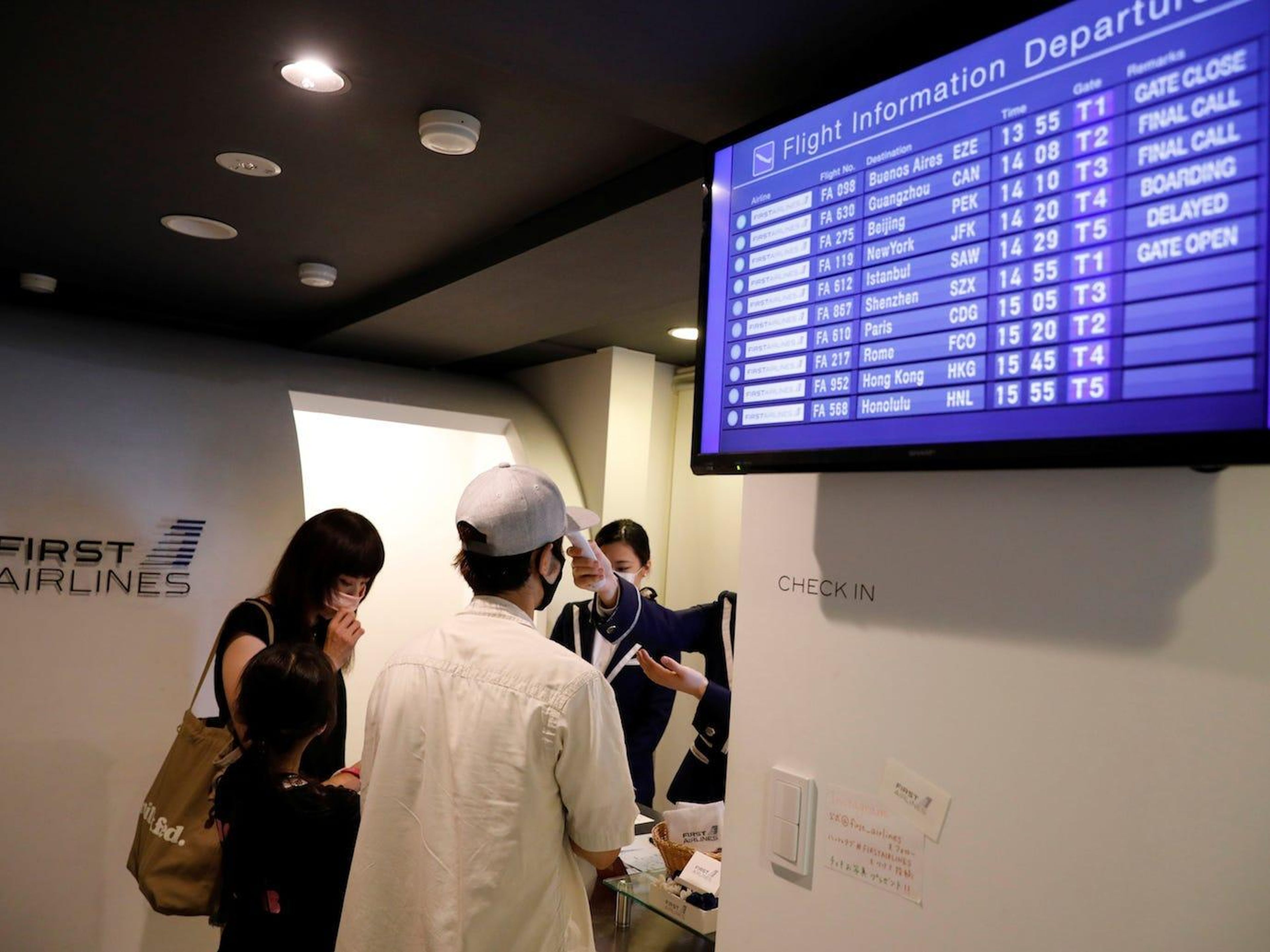 A staff dressed as a flight attendant checks temperature of a customer at a check-in desk at First Airlines in Tokyo, Japan, on August 12, 2020. Kim Kyung-Hoon/Reuters