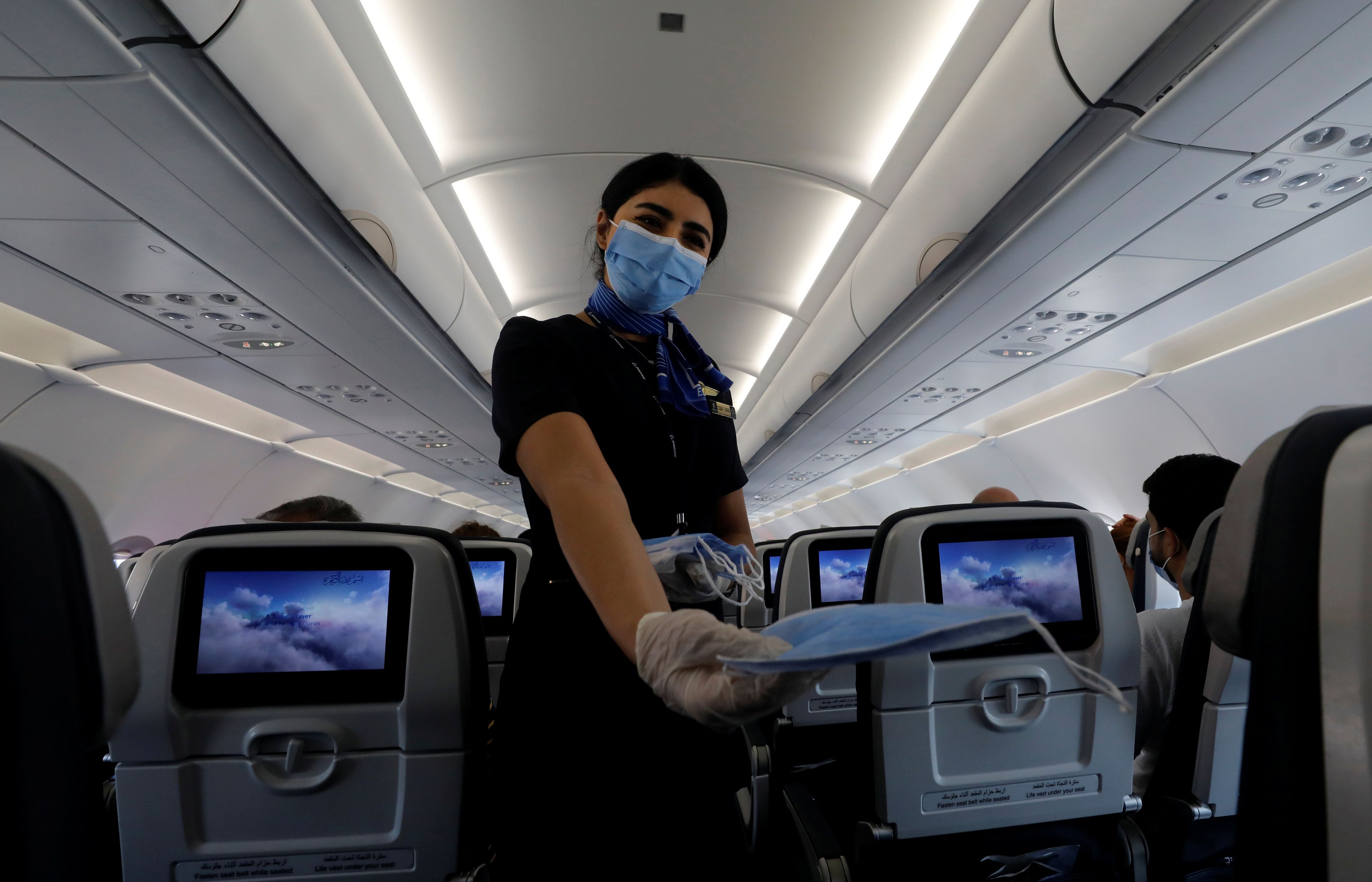 Azafata repartiendo mascarillas en un avión durante la pandemia del coronavirus
