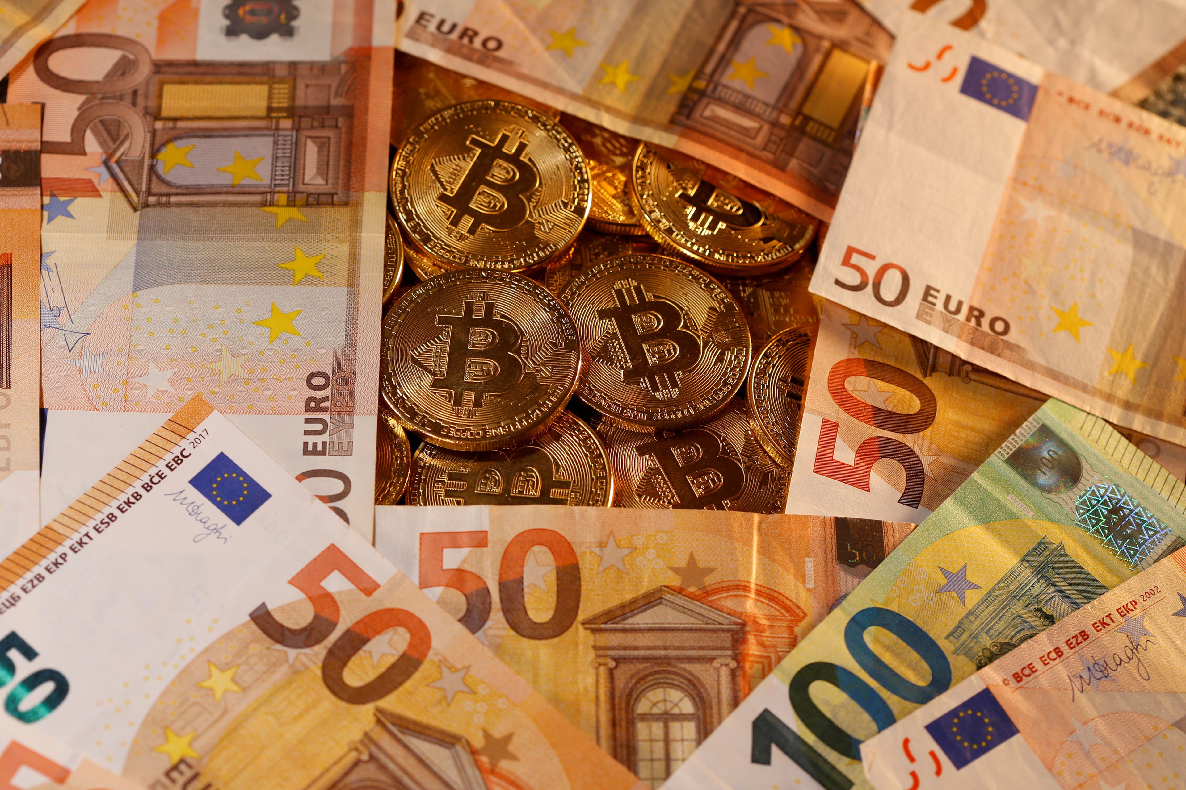 Billetes de euro junto a representaciones de bitcoins