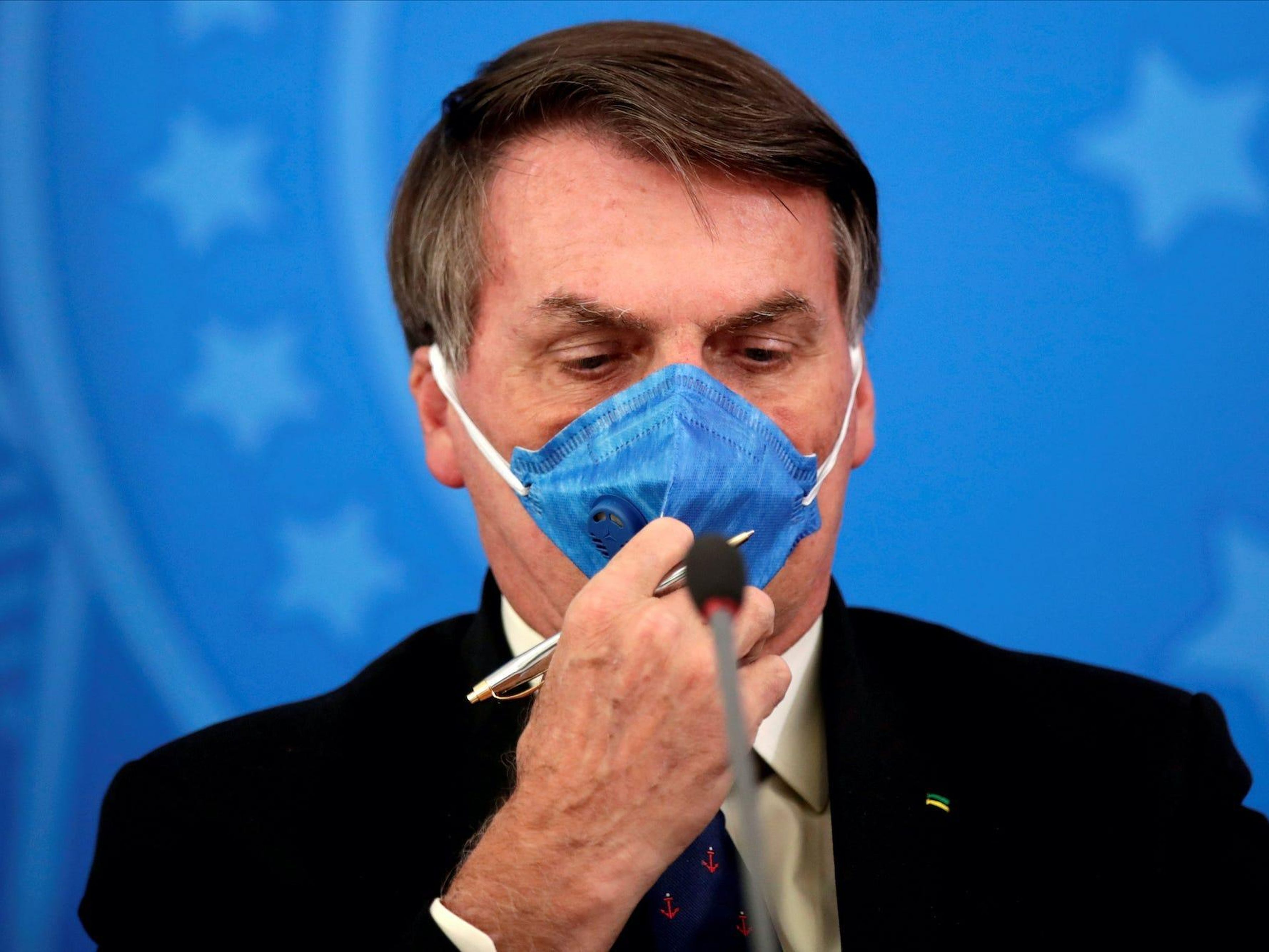 Brazil's President Jair Bolsonaro adjusts his protective face mask at a press statement during the coronavirus disease (COVID-19) outbreak in Brasilia, Brazil, March 20, 2020. Picture taken March 20, 2020. Ueslei Marcelino/Reuters