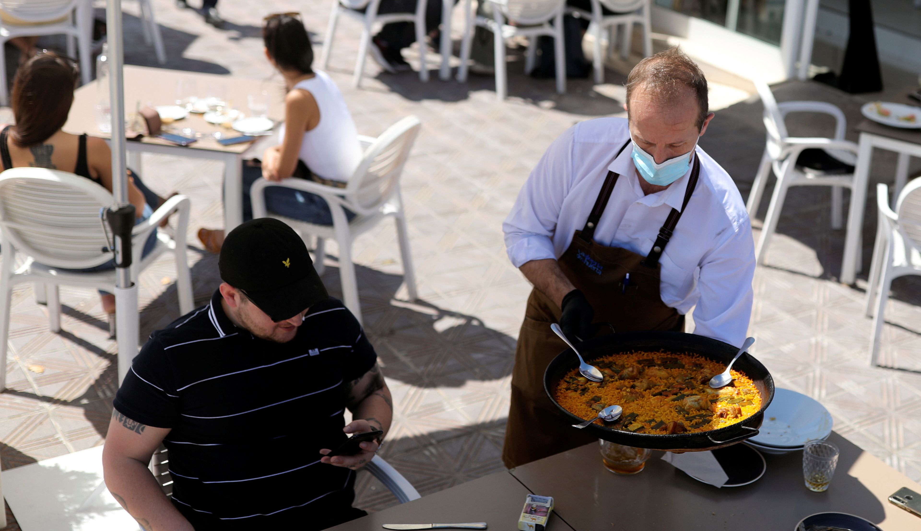 Un camarero sirve paella en una terraza de Valencia