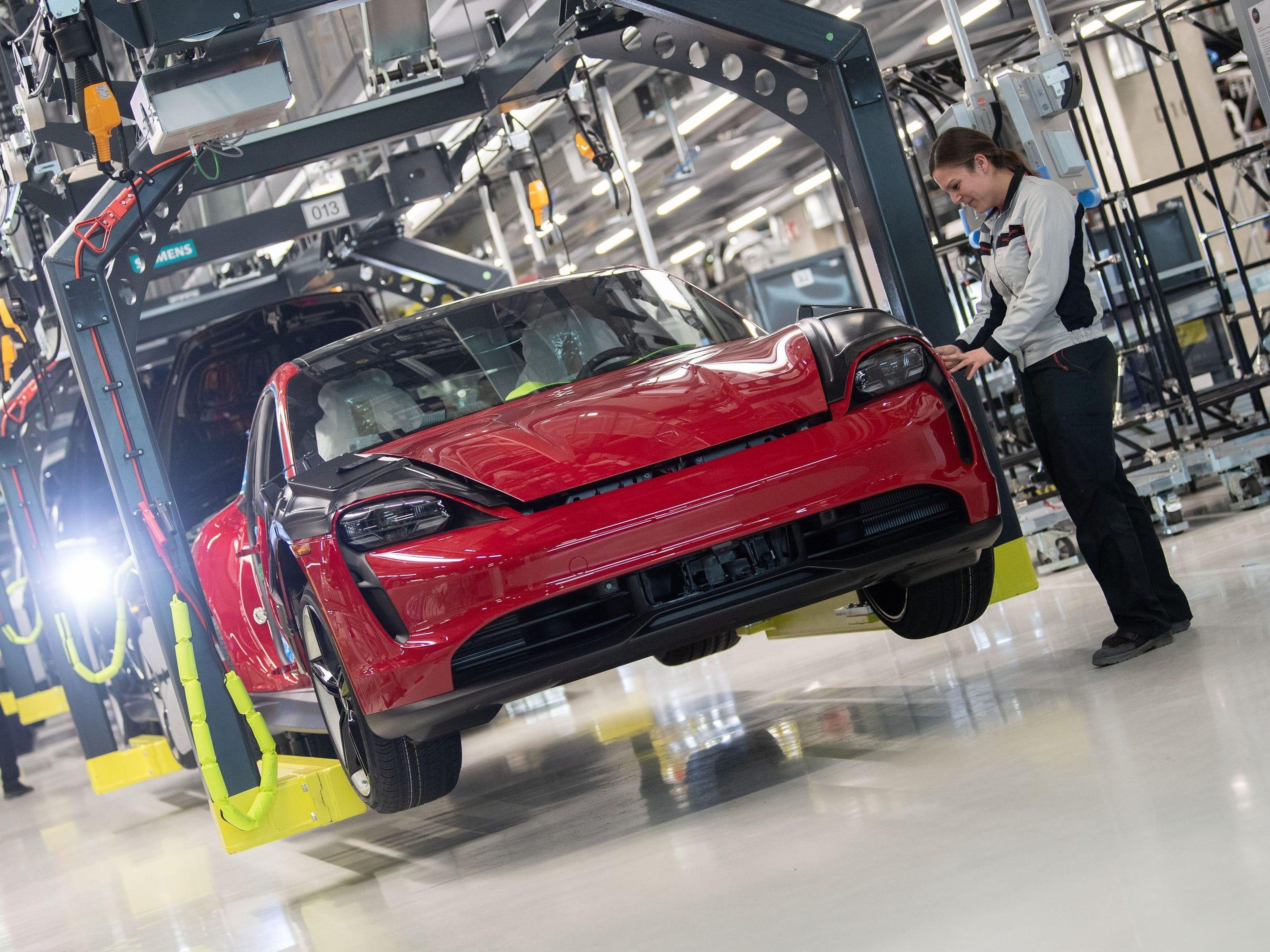 An employee of Porsche AG checks a Porsche Taycan in production.