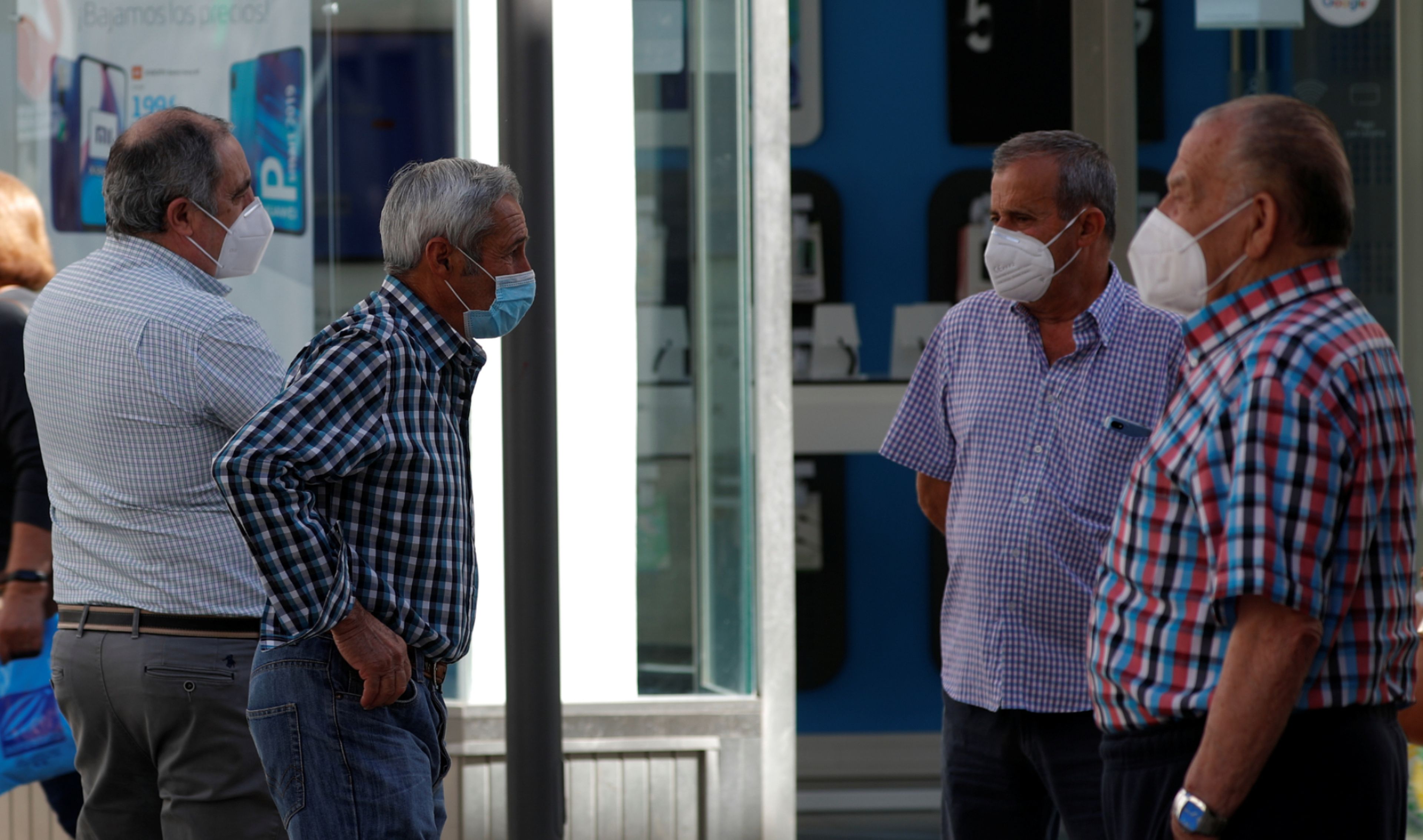 Un grupo de jubilados con mascarilla conversan en una calle de Ronda (Málaga)