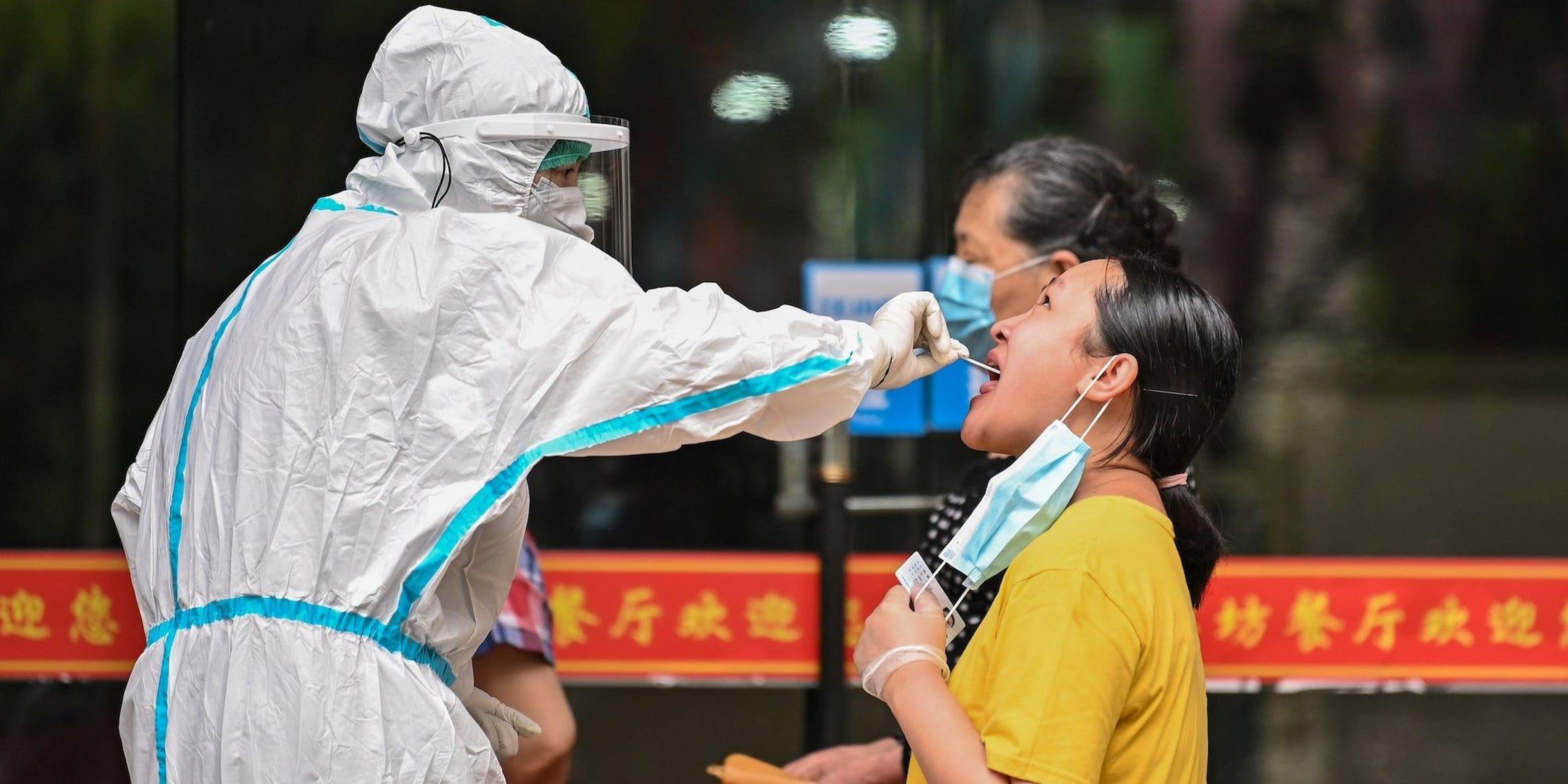 Un trabajador médico toma una muestra de hisopo de un hombre para ser analizada por el coronavirus COVID-19 junto a una calle en Wuhan, en el centro de la provincia china de Hubei el 16 de mayo de 2020