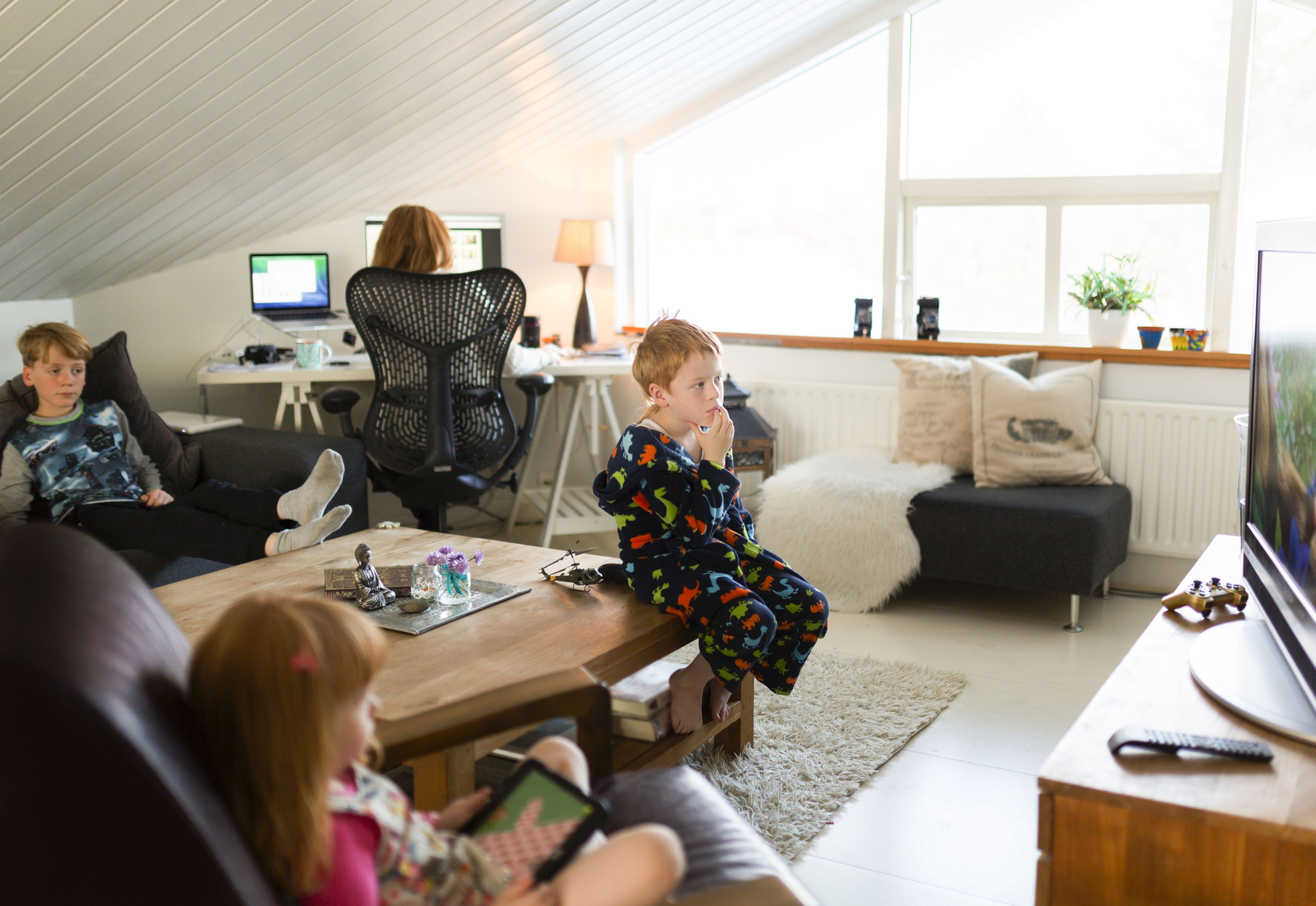 Niños viendo la tele mientras adulto trabaja