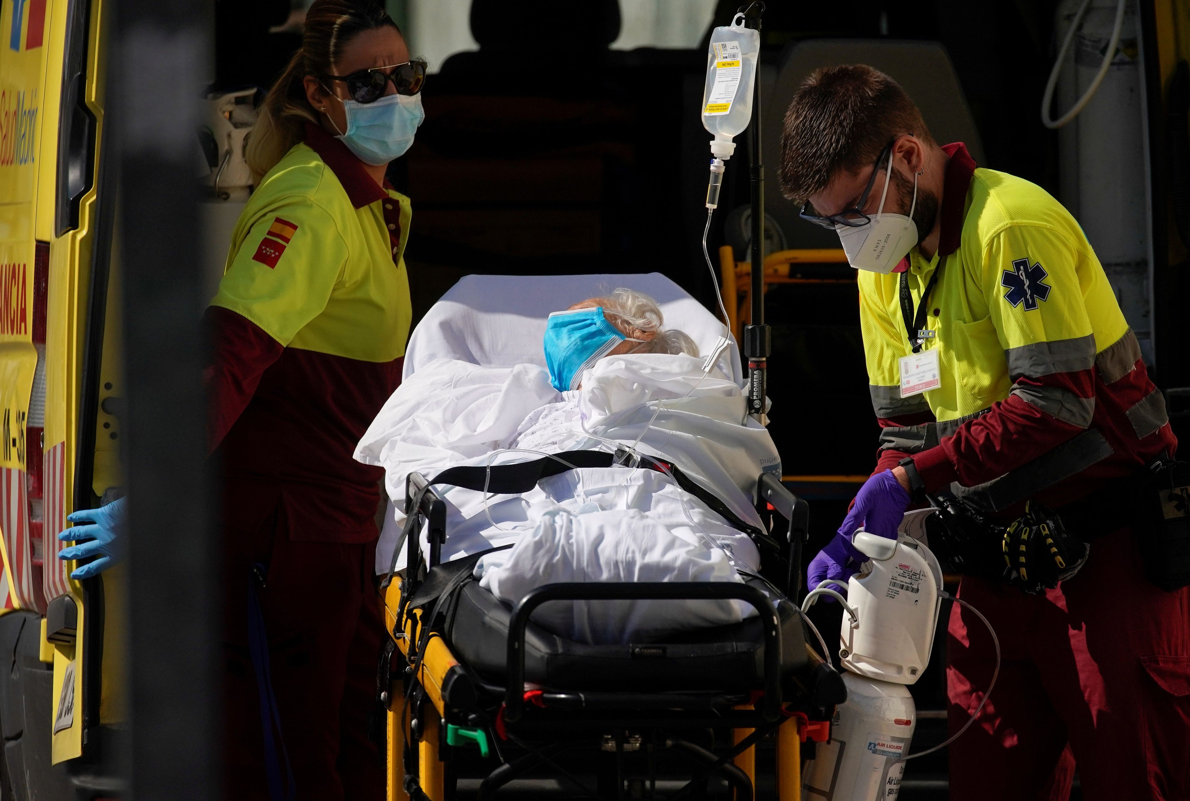 Sanitarios meten a un paciente en camilla dentro de una ambulancia.