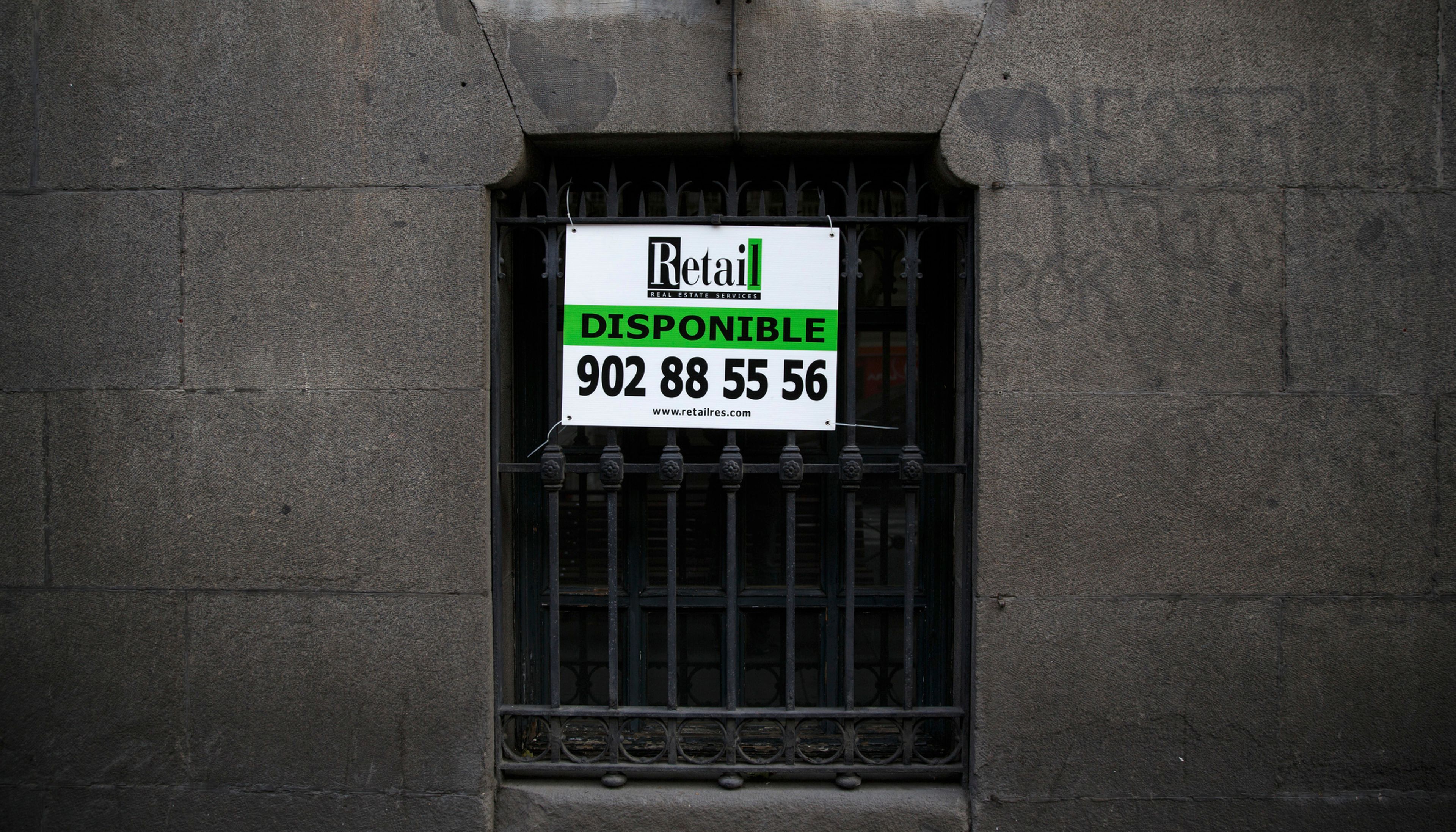 Un anuncio de una inmobiliaria en la ventana de un bajo en Madrid