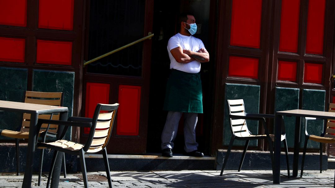 Un camarero con mascarilla a las puertas de un bar en Madrid, España.