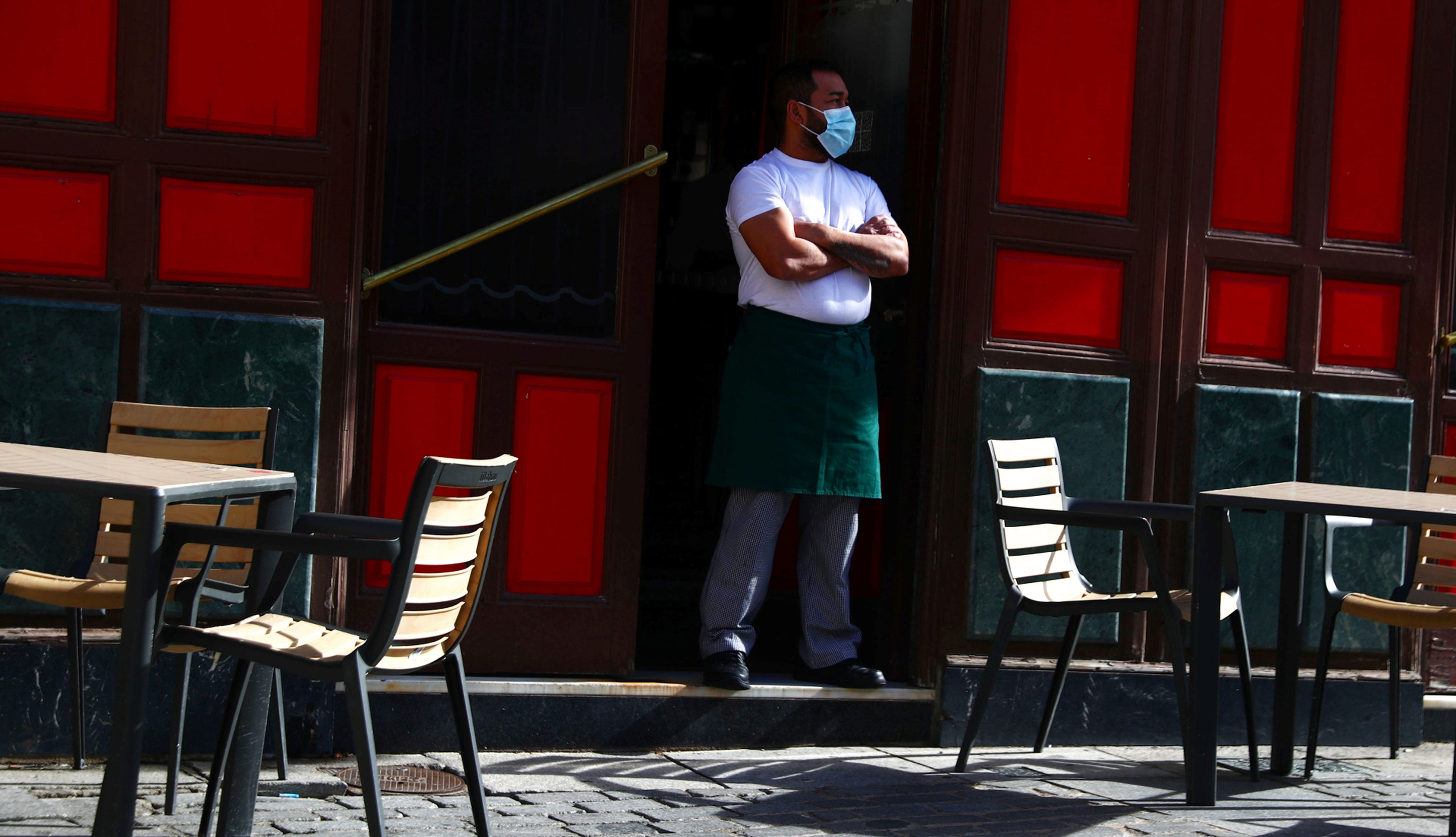 Un camarero con mascarilla ante una terraza vacía en Madrid