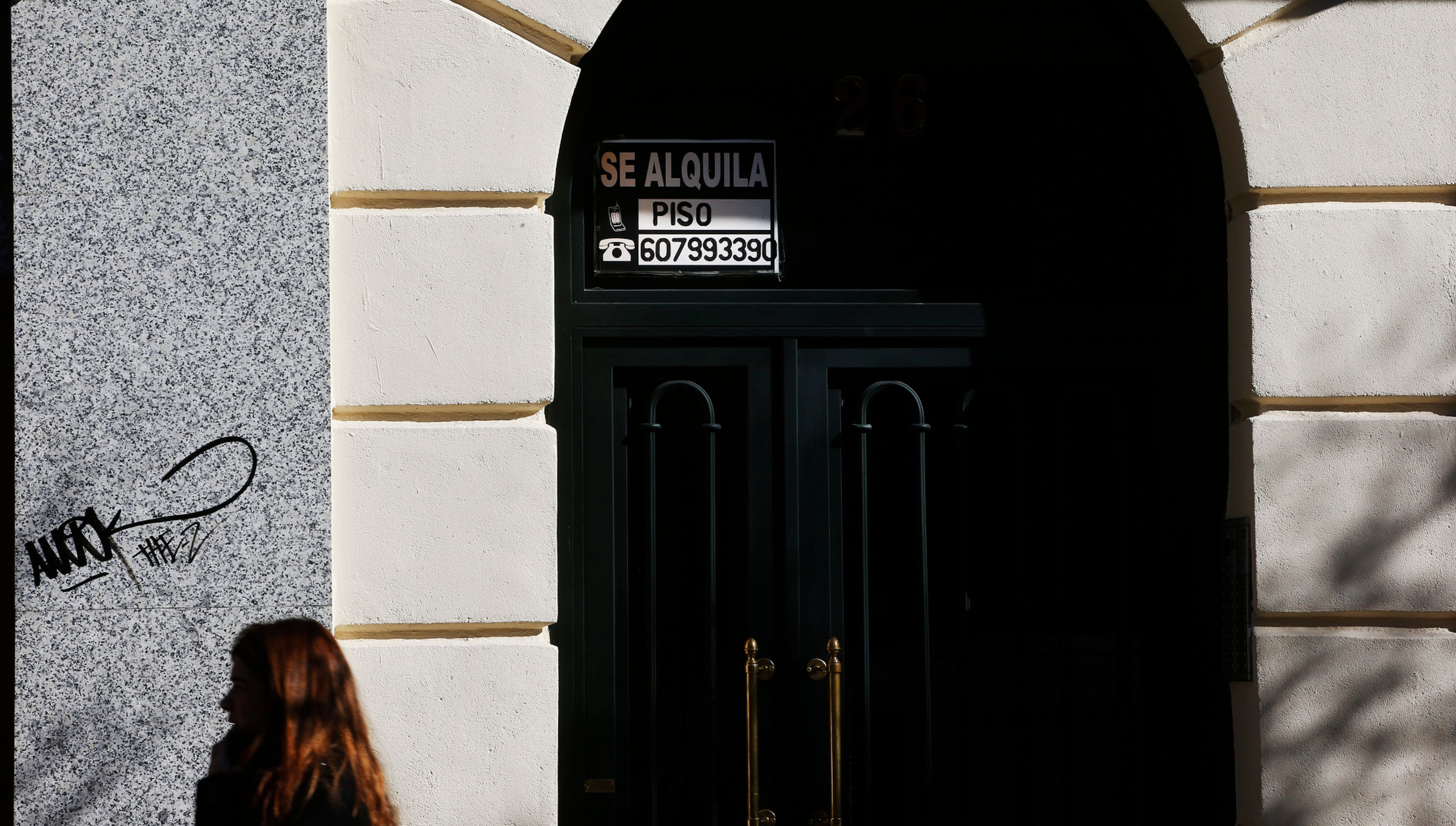 Una joven pasa ante un anuncio de un piso en alquiler en Madrid