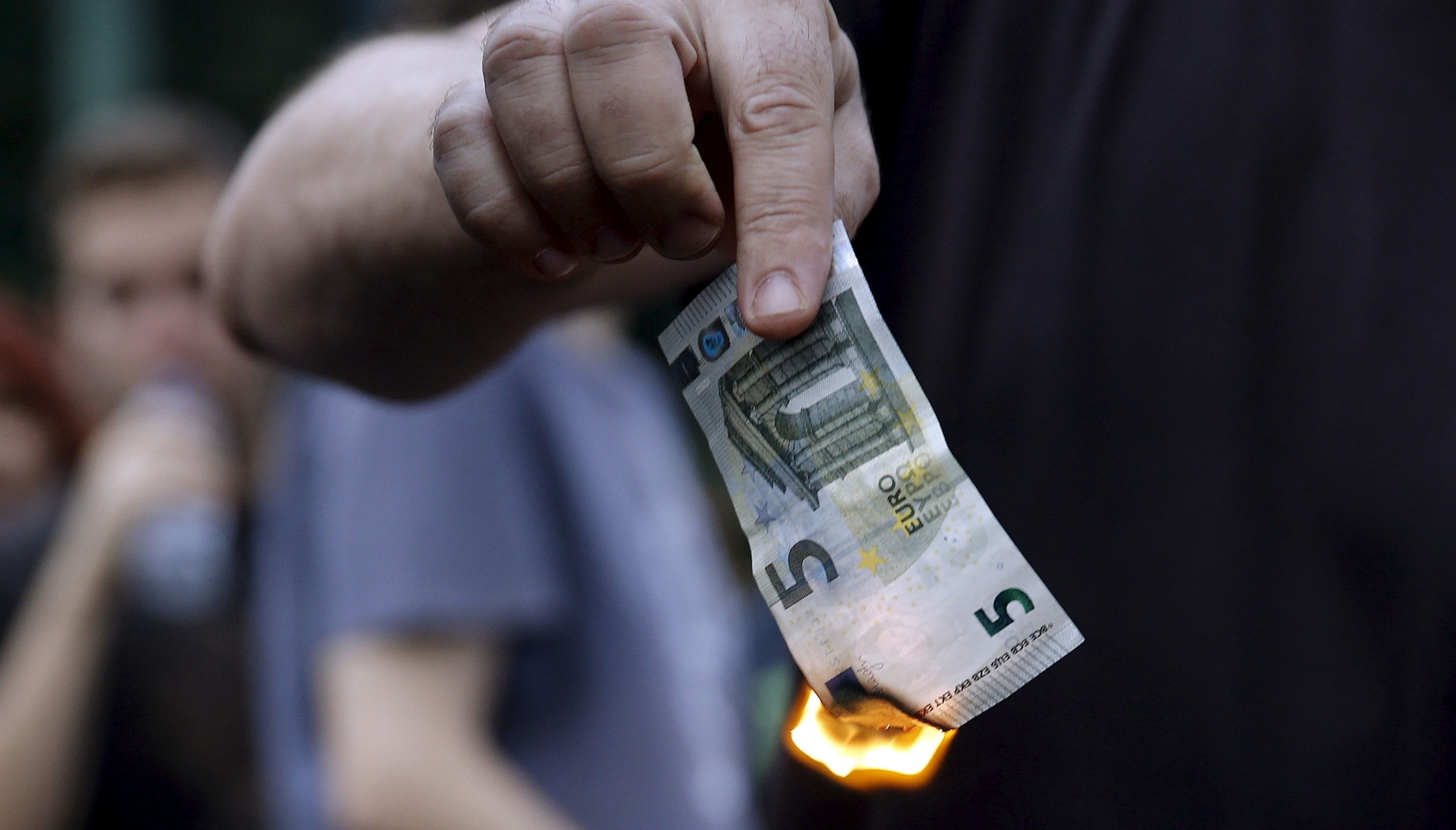 Un manifestante quema un billete de 5 euros en una protesta contra las medidas de austeridad en Grecia