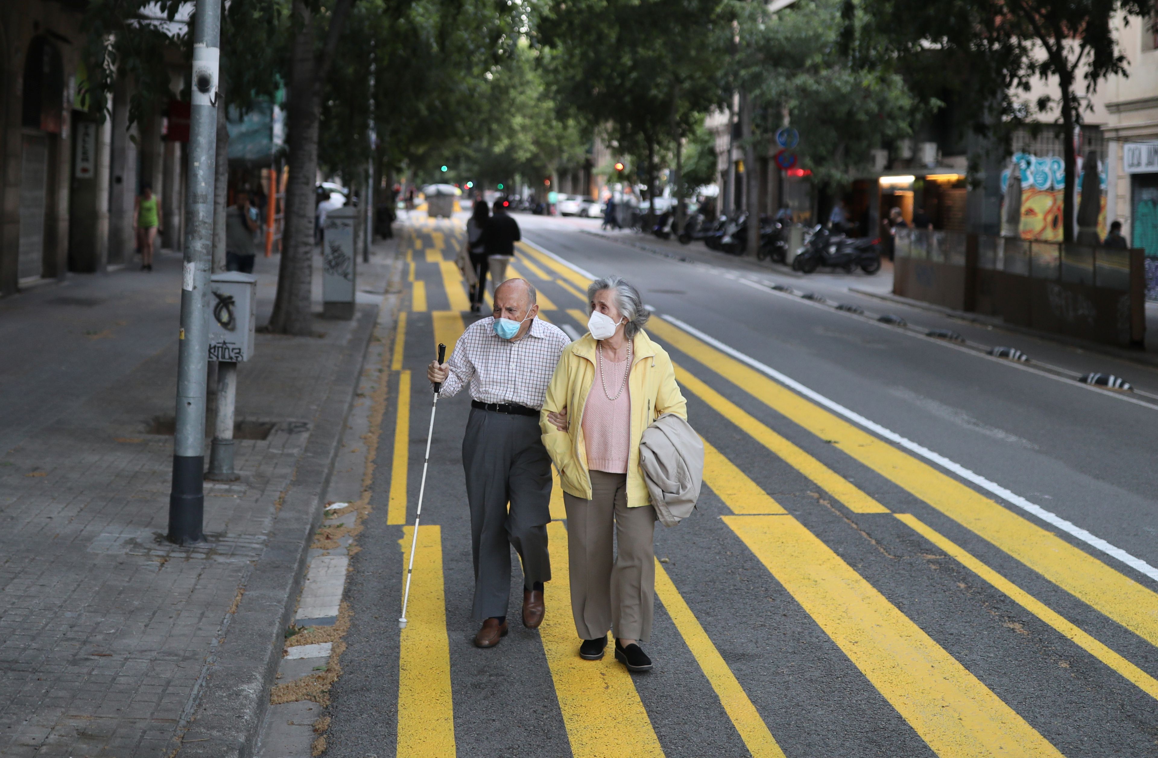 Una pareja de ancianos pasea con mascarilla