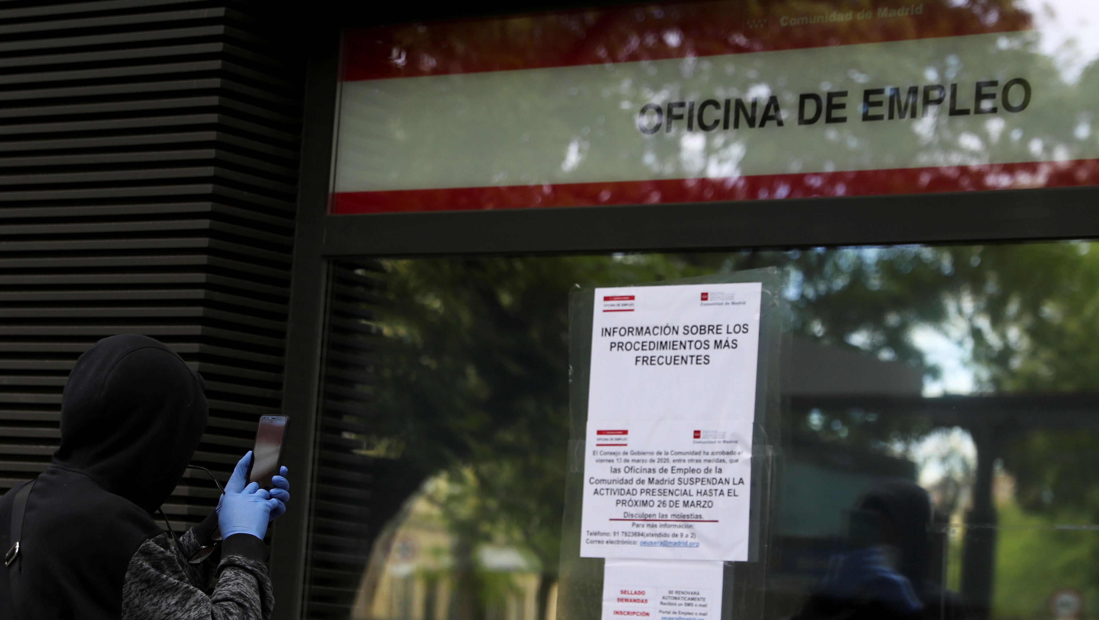 Una persona fotografía los avisos ante el coronavirus en una oficina de empleo de Madrid
