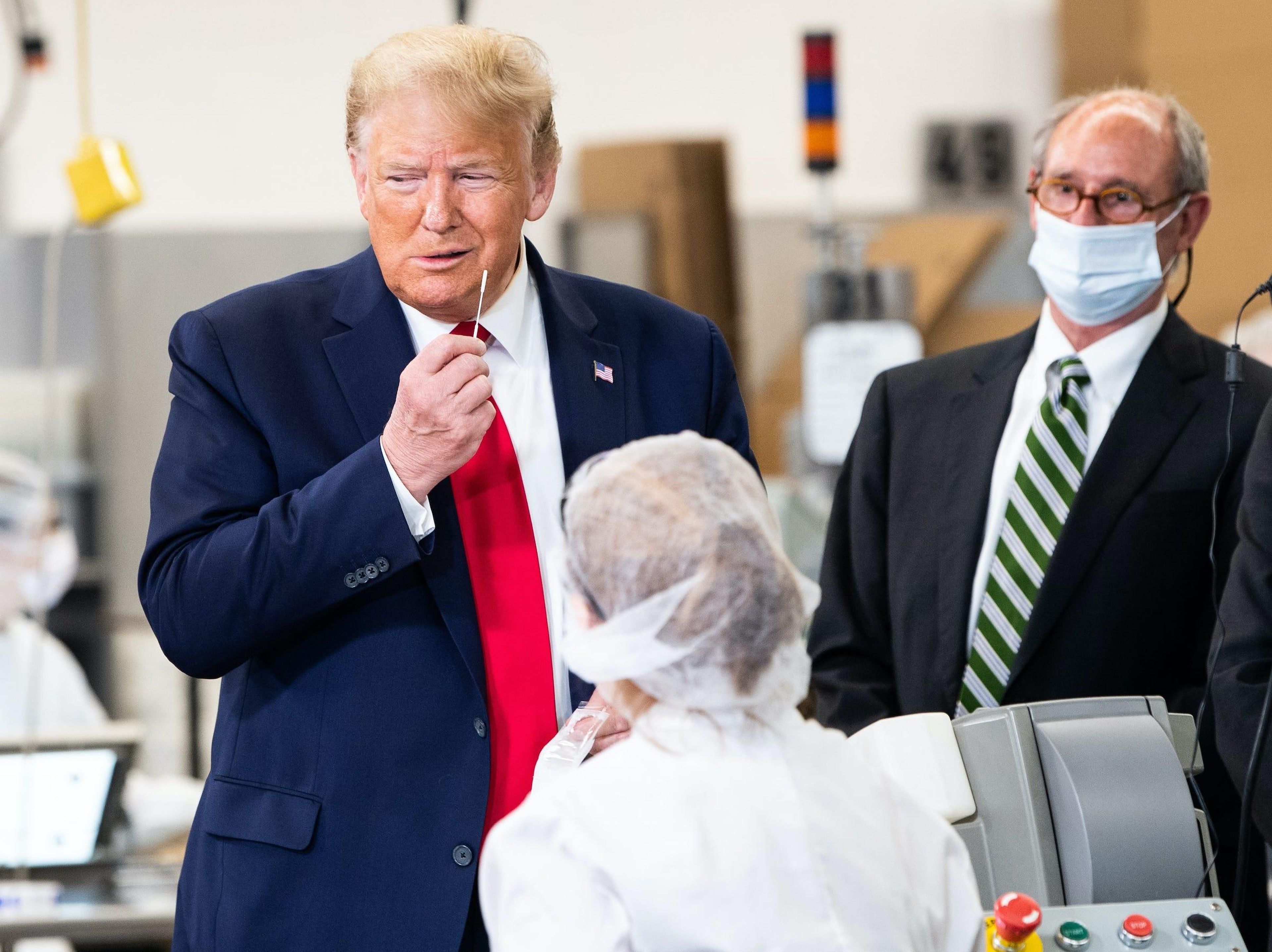 El presidente de Estados Unidos Donald Trump simula tomar una prueba de COVID-19 sosteniendo un hisopo durante su visita a las instalaciones de Puritan Medical Products en Guilford, Maine, el 5 de junio de 2020.