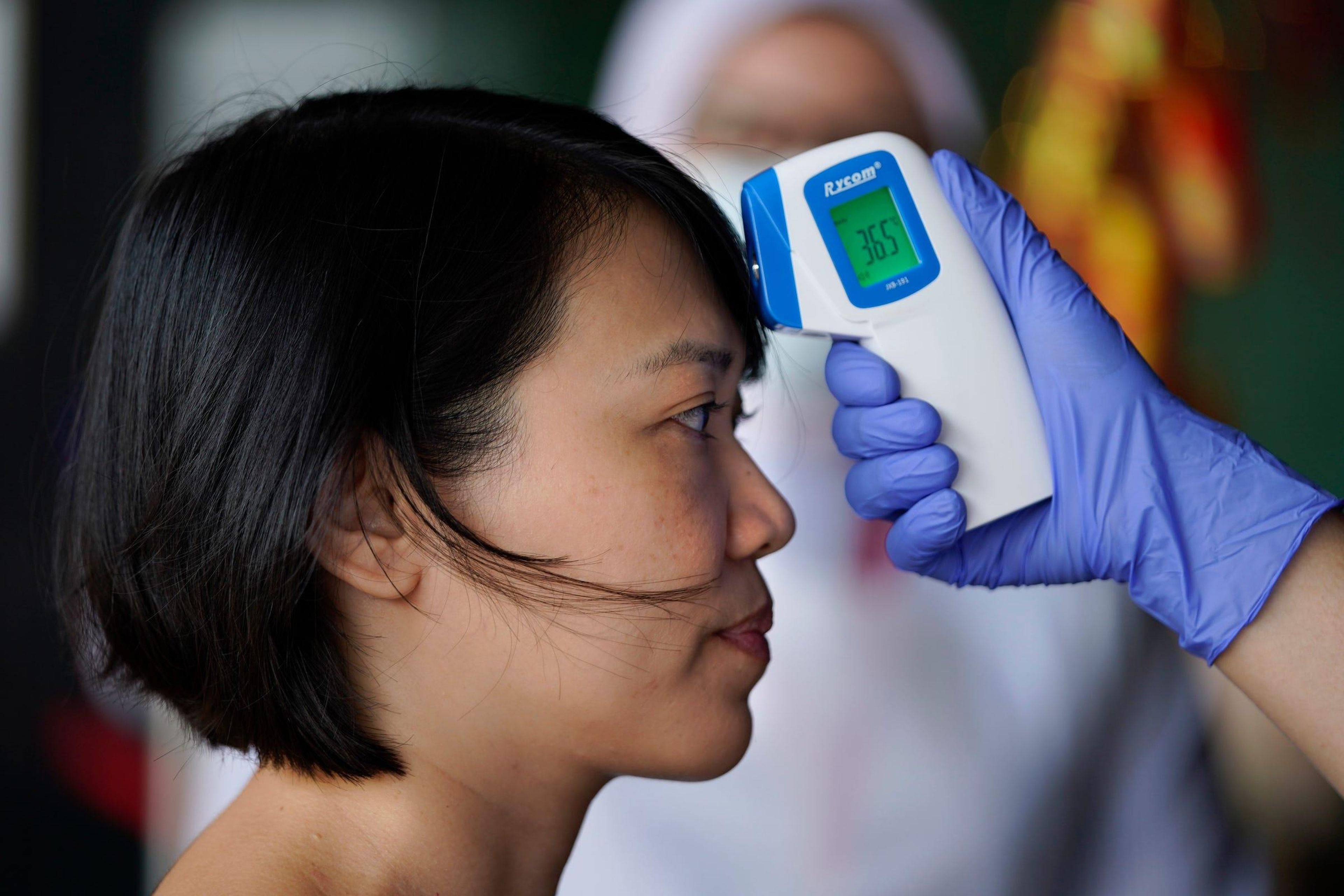 Una mujer se toma la temperatura corporal en medio de un brote de coronavirus.