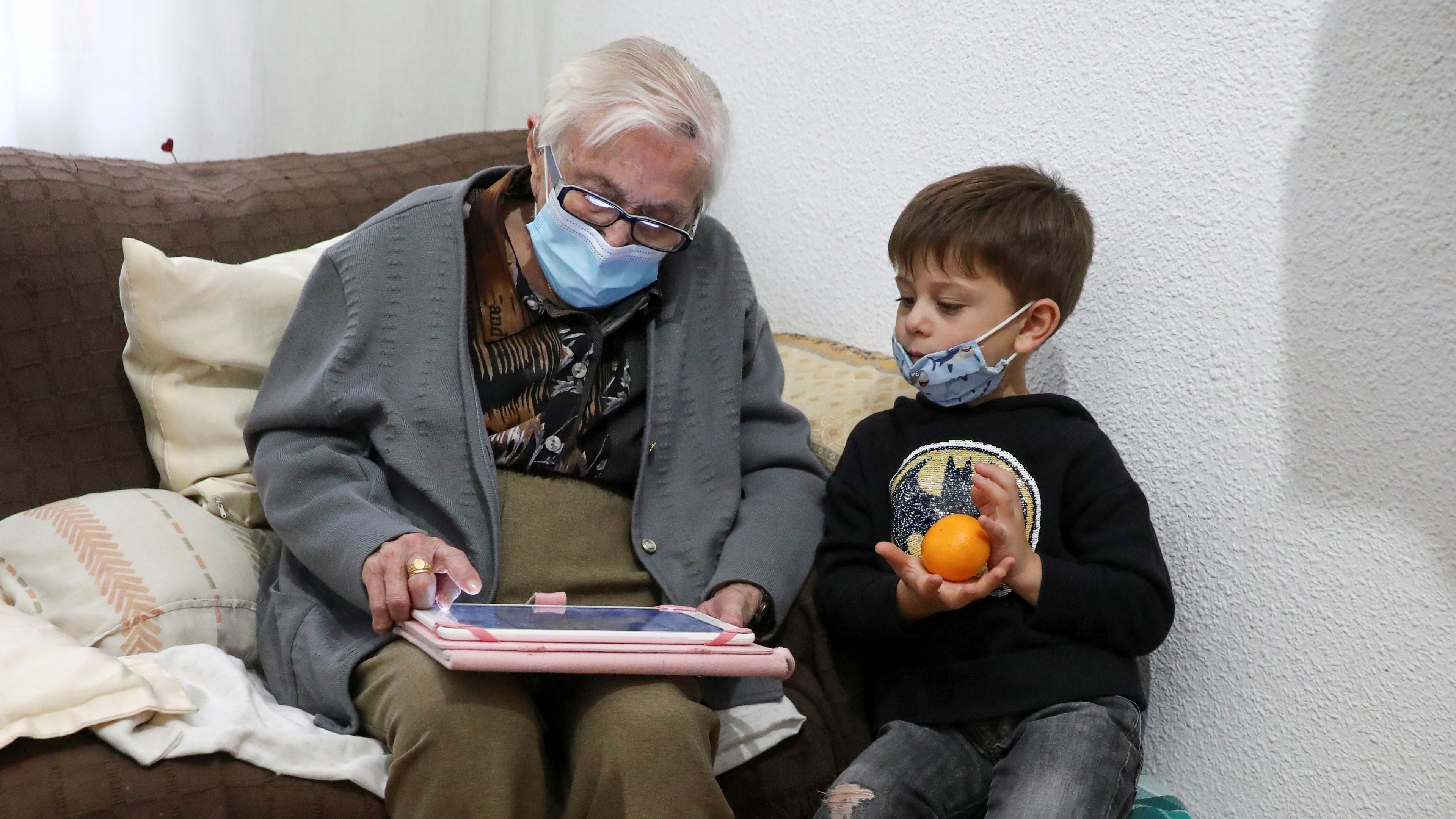 Una abuela y su nieto miran una tablet durante la pandemia de coronavirus