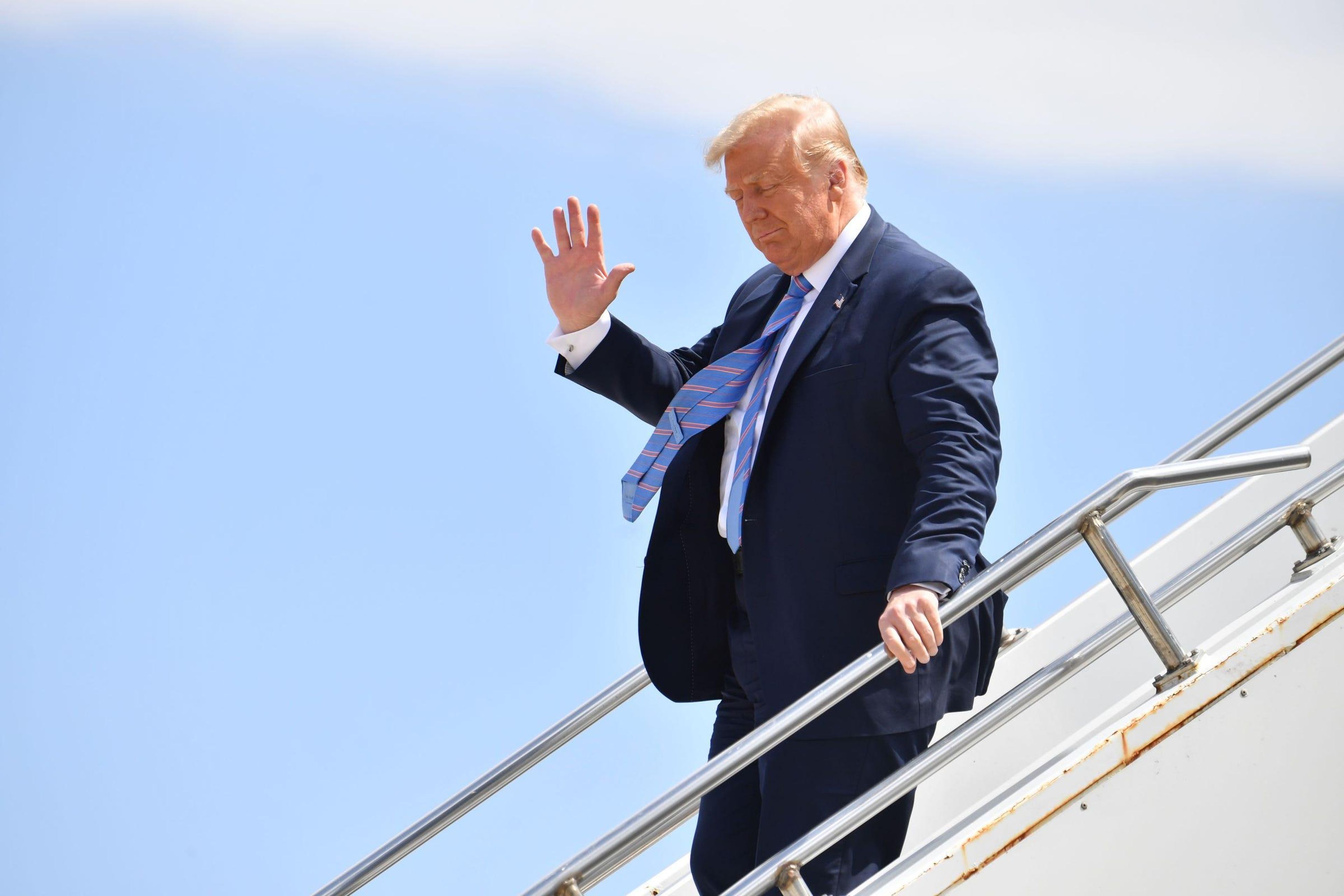 US President Donald Trump waves as he walks off Air Force One.