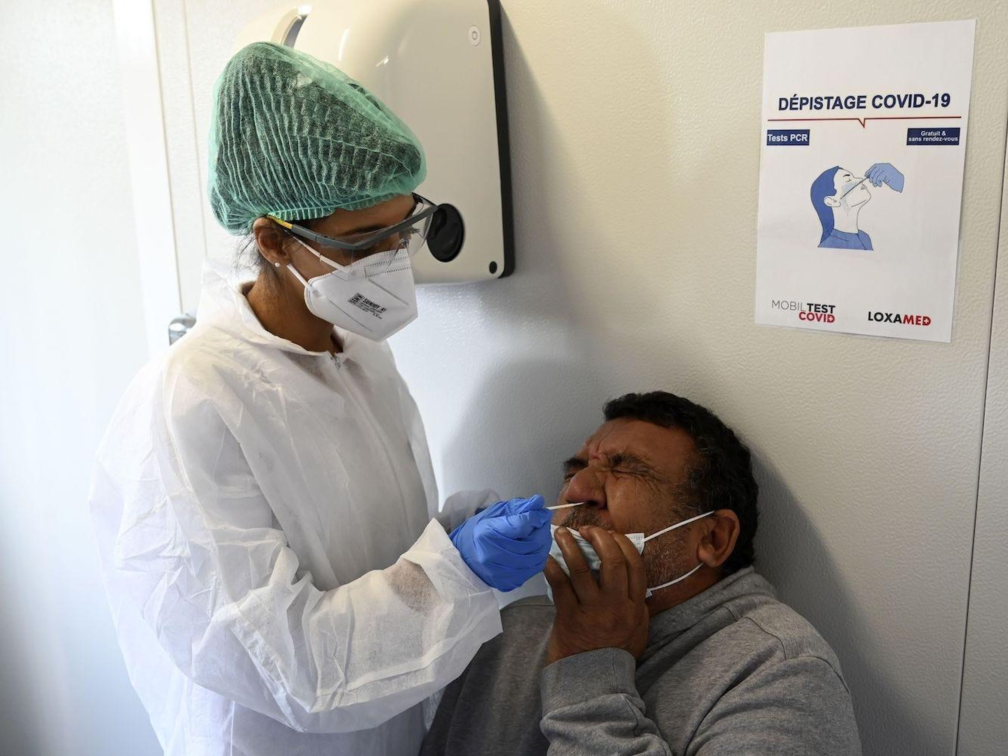 Una trabajadora médica toma un hisopo de la nariz de un hombre mientras administra una nueva prueba de coronavirus en una unidad móvil de pruebas en la principal estación de trenes de Marsella, en el sur de Francia, el 12 de noviembre de 2020.