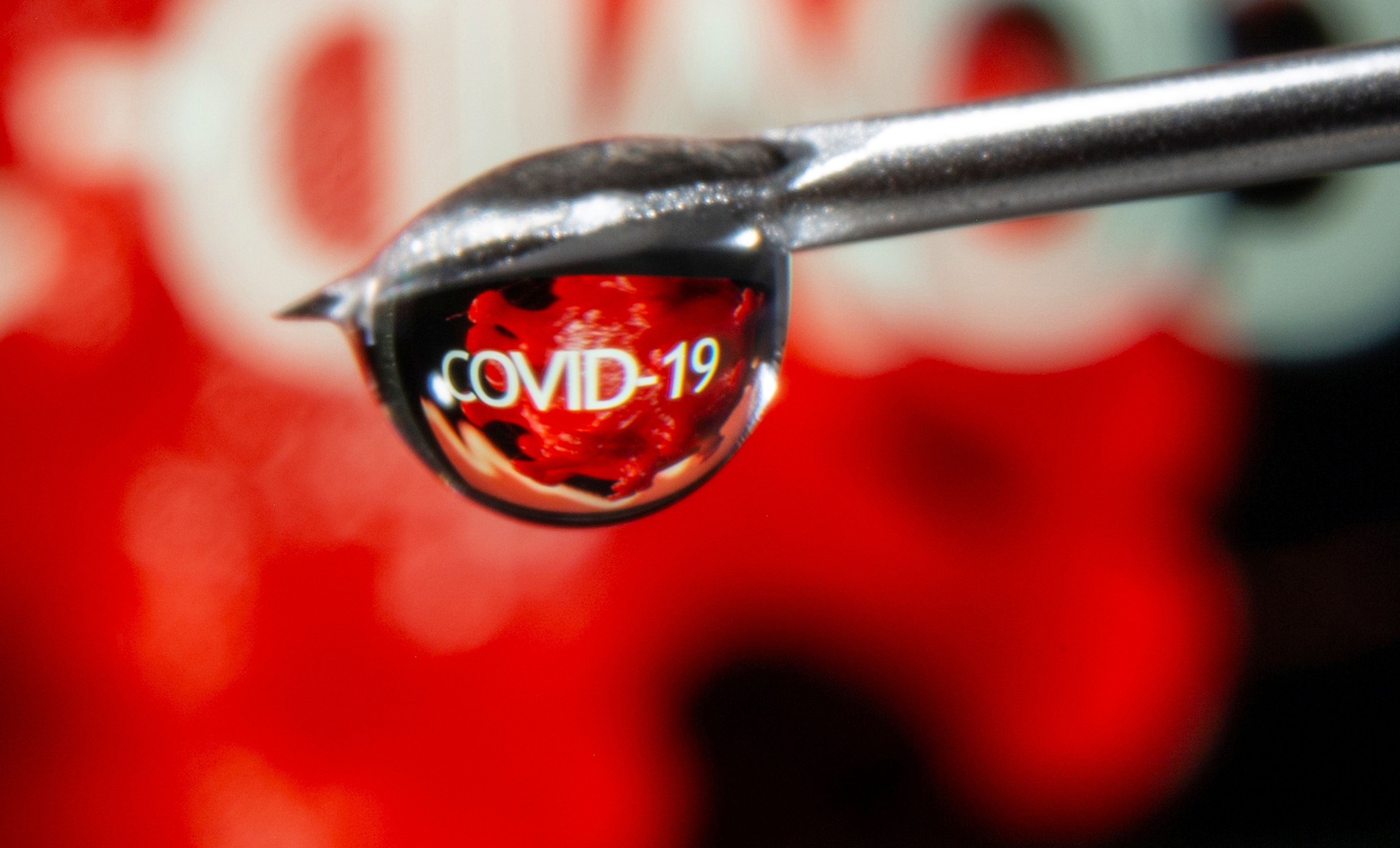 Una gota refleja la palabra COVID-19 en una jeringuilla