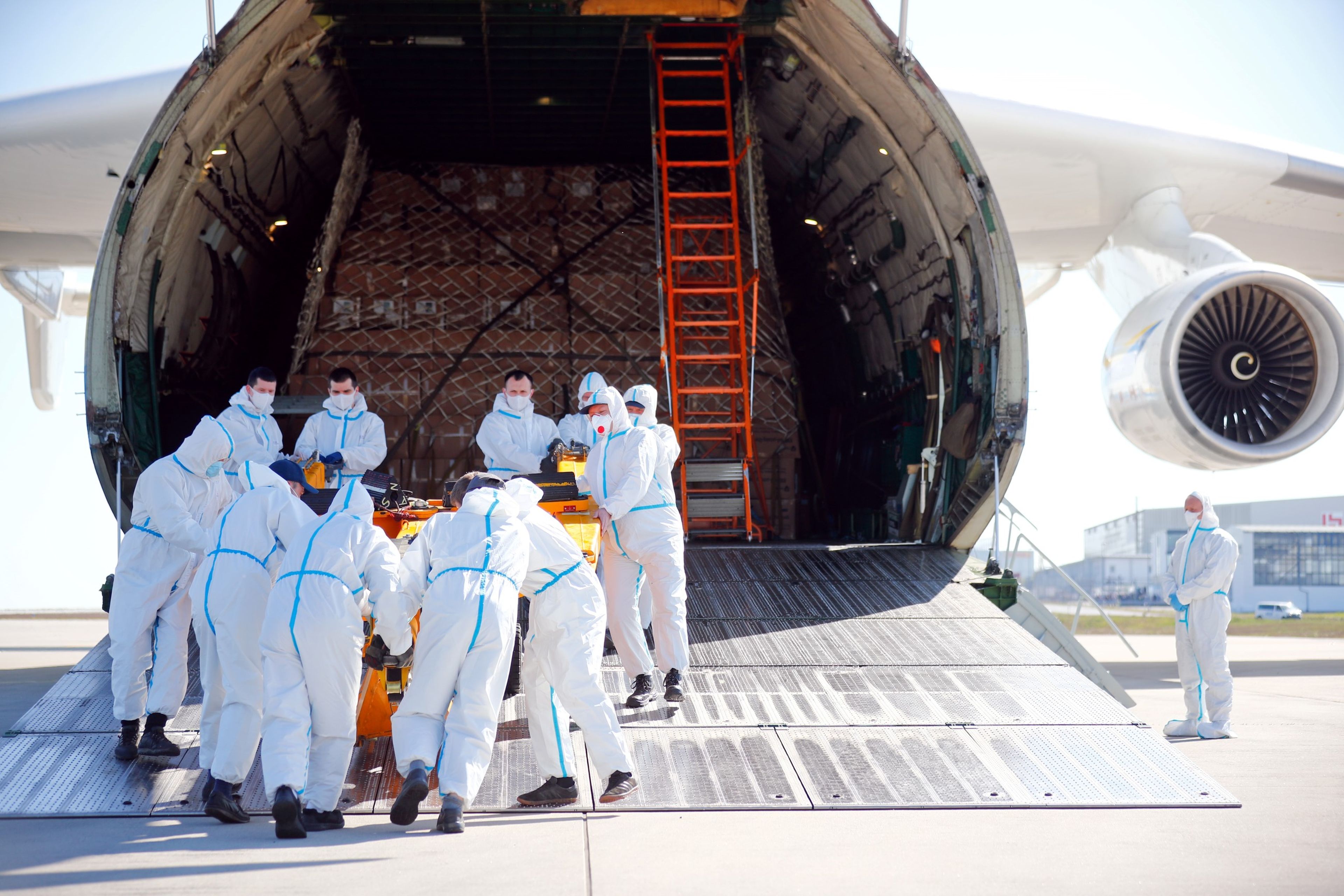 Un grupo de operarios trata de cargar suministros médicos en un avión durante la pandemia del coronavirus