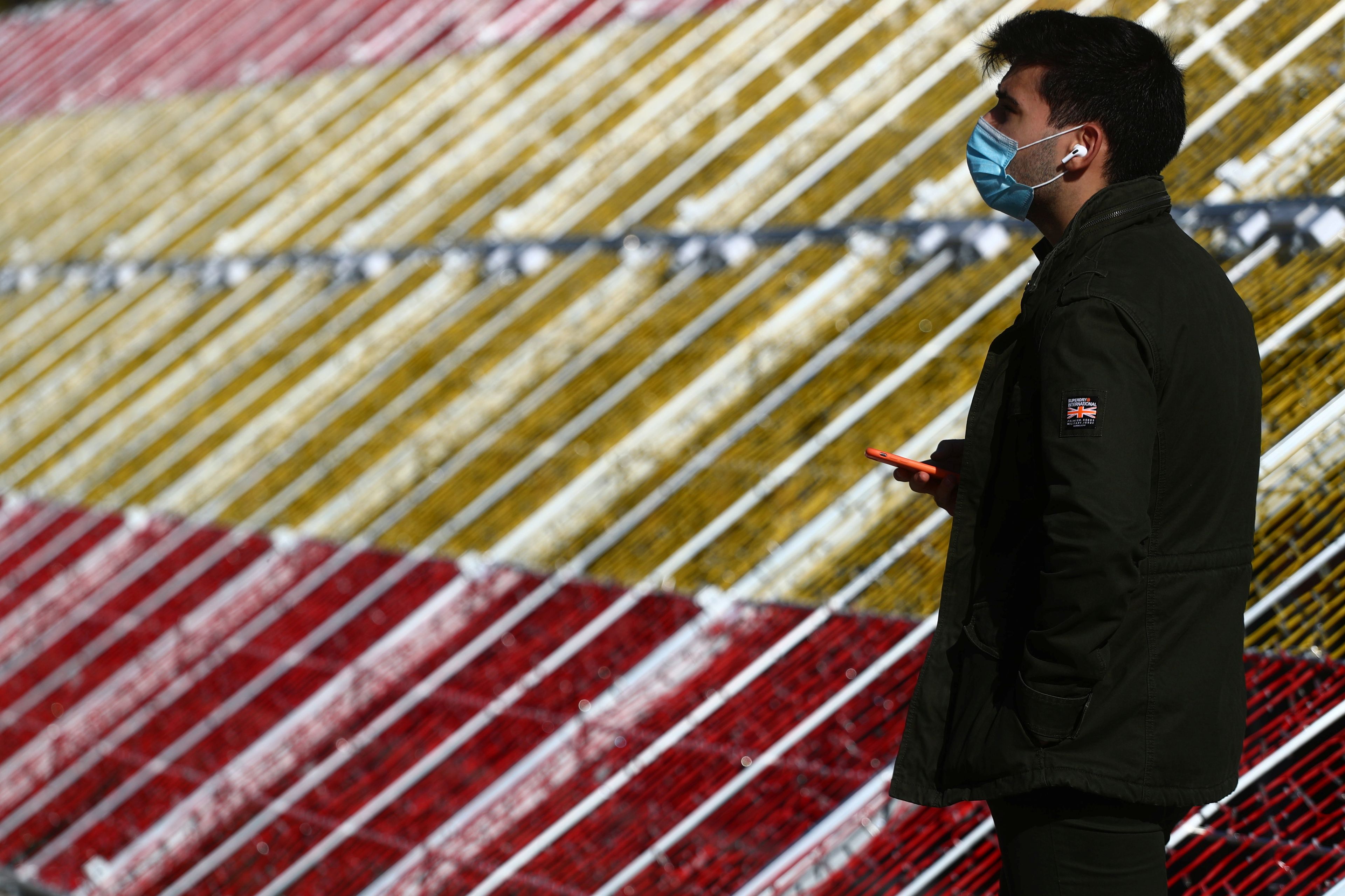 Un joven pasea por el centro de Madrid con el alumbrado de Navidad decorado con la bandera de España en medio de la pandemia del coronavirus