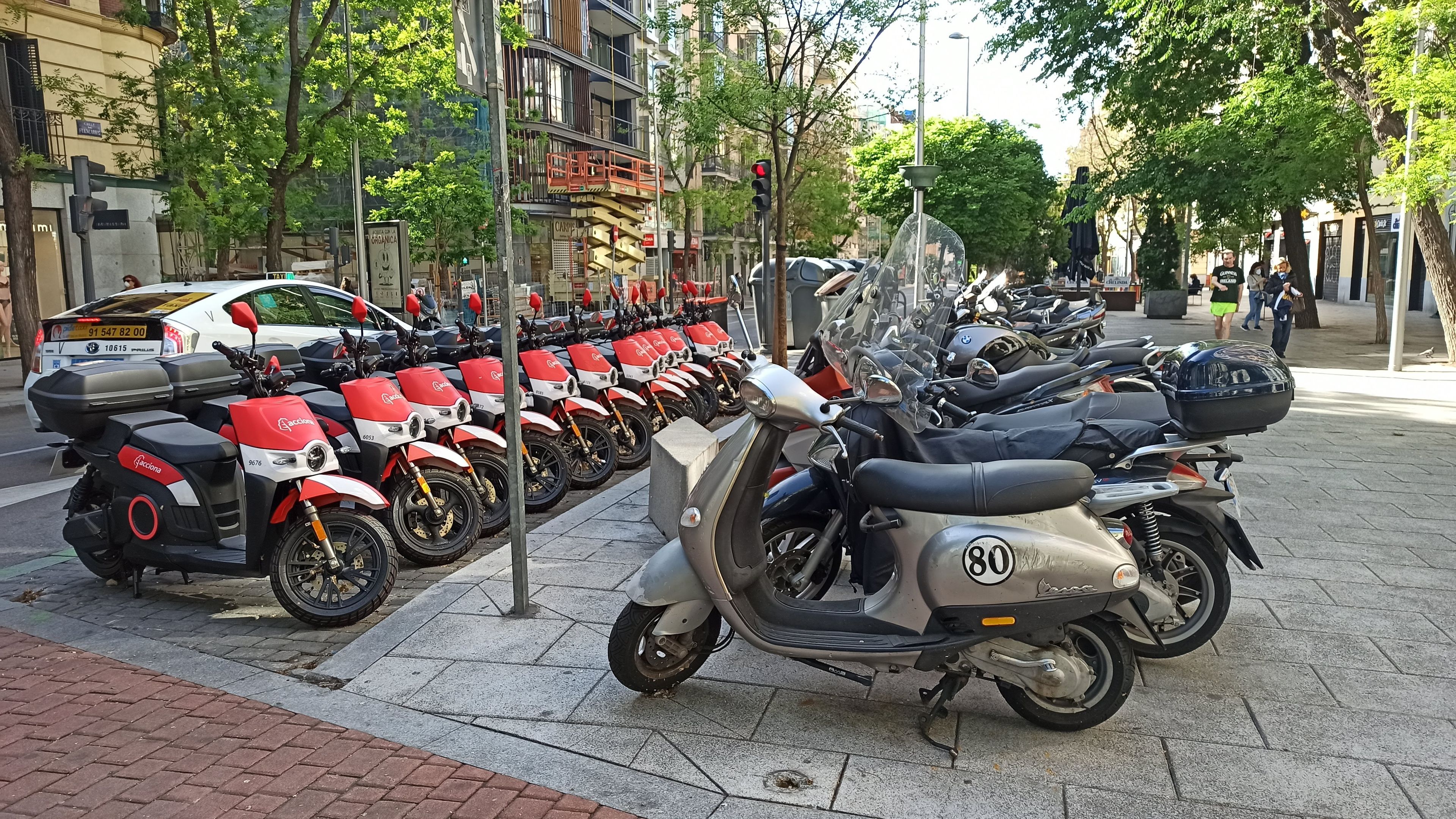 Motos eléctricas compartidas de Acciona ocupando toda una zona de aparcamiento en la calle Fuencarral, en Madrid.