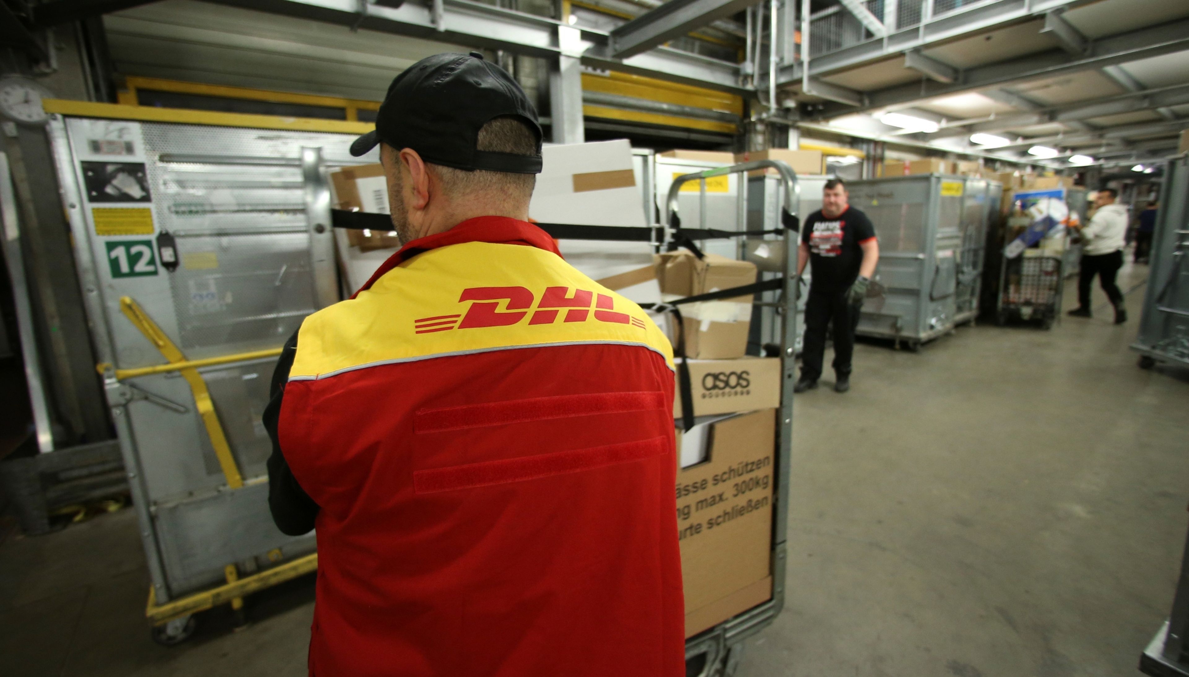 Un operario de DHL mueve un carro con paquetes en un almacén en Alemania