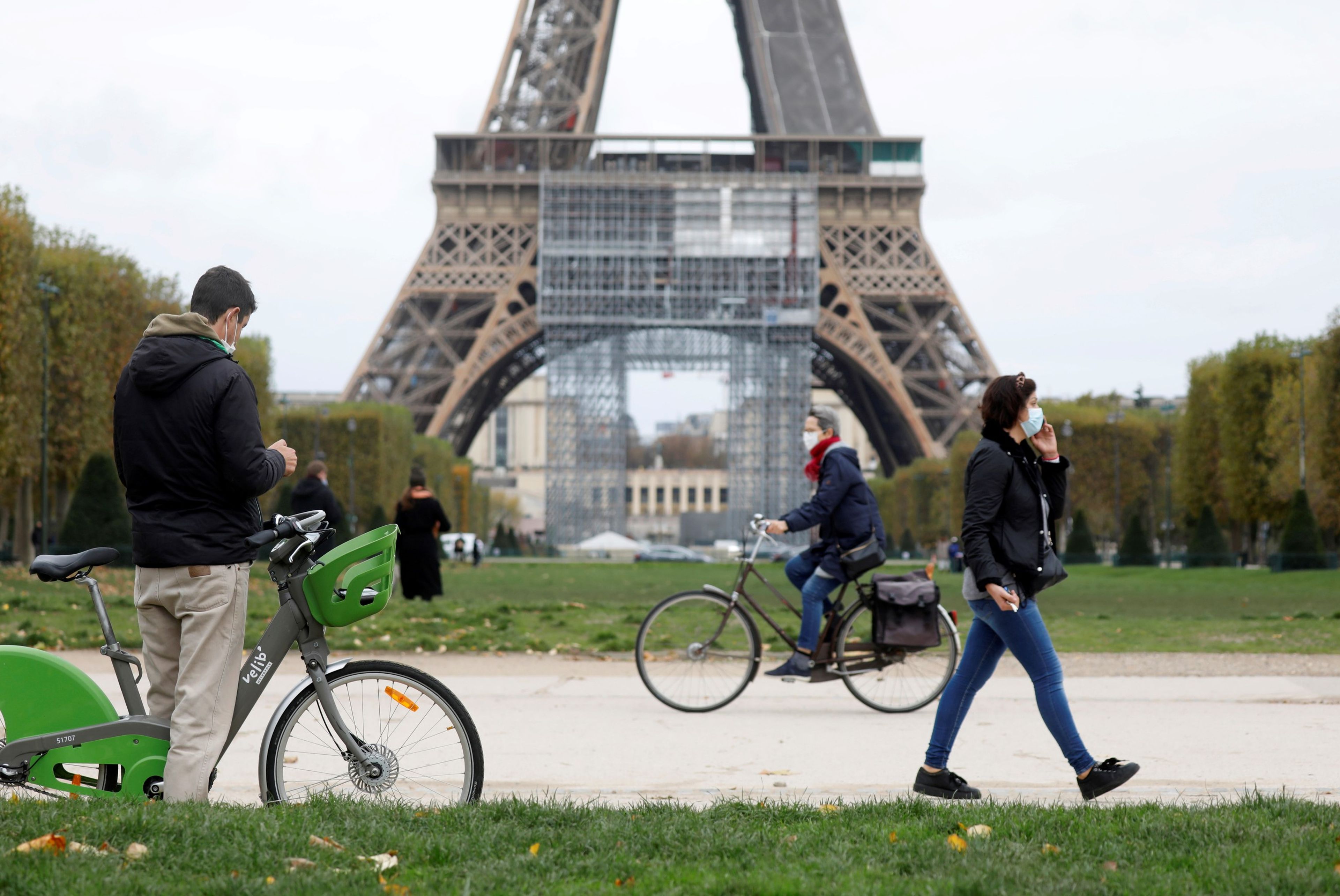 Varias personas pasean por delante de la Torre Eiffel de París
