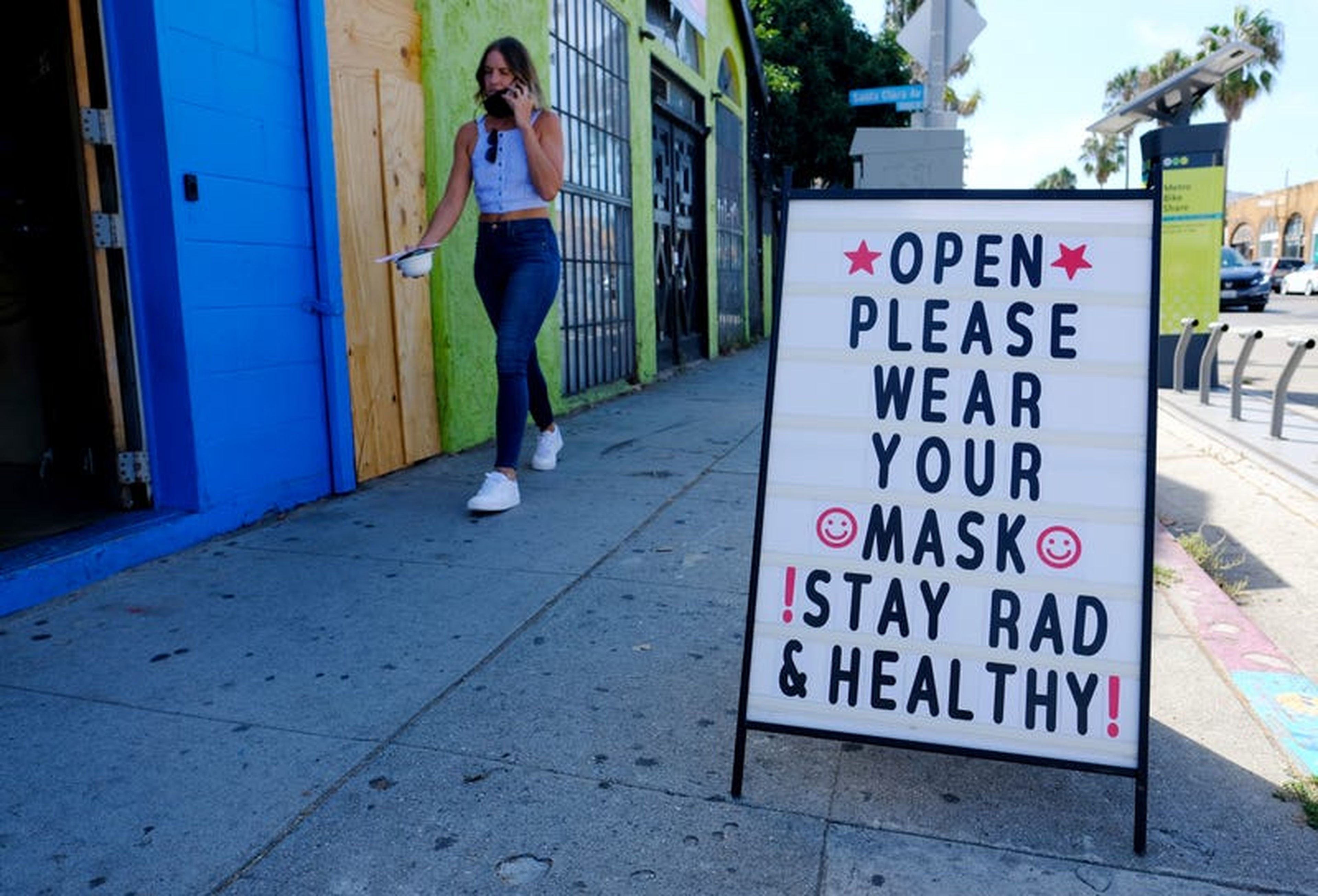 A woman walks past a recently reopened shop on Abbot Kinney Boulevard on August 26, 2020, in Venice, California.