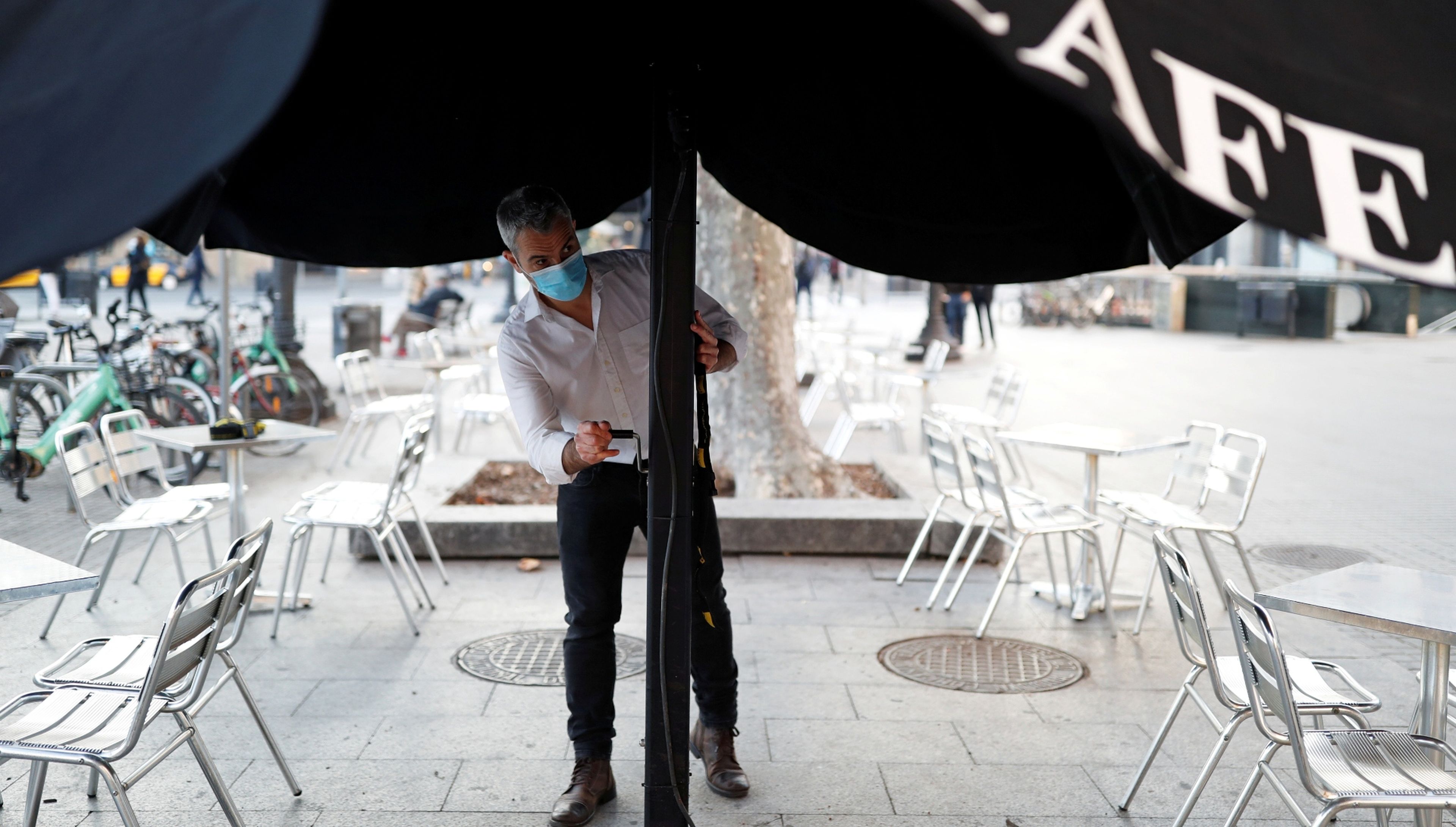 Un camarero abre una sombrilla en una terraza de Barcelona