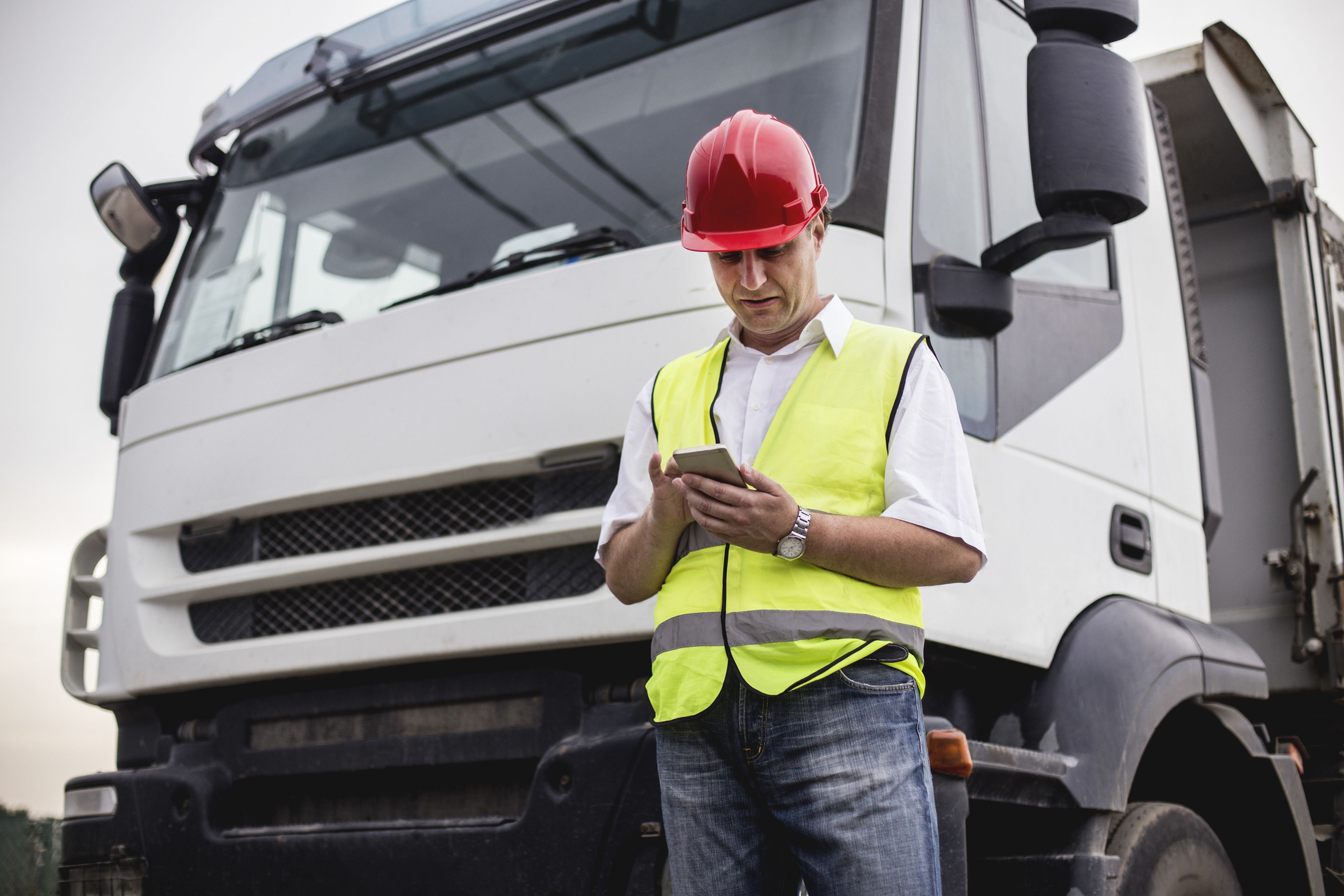 Un camionero consulta su tablet delante del camión.