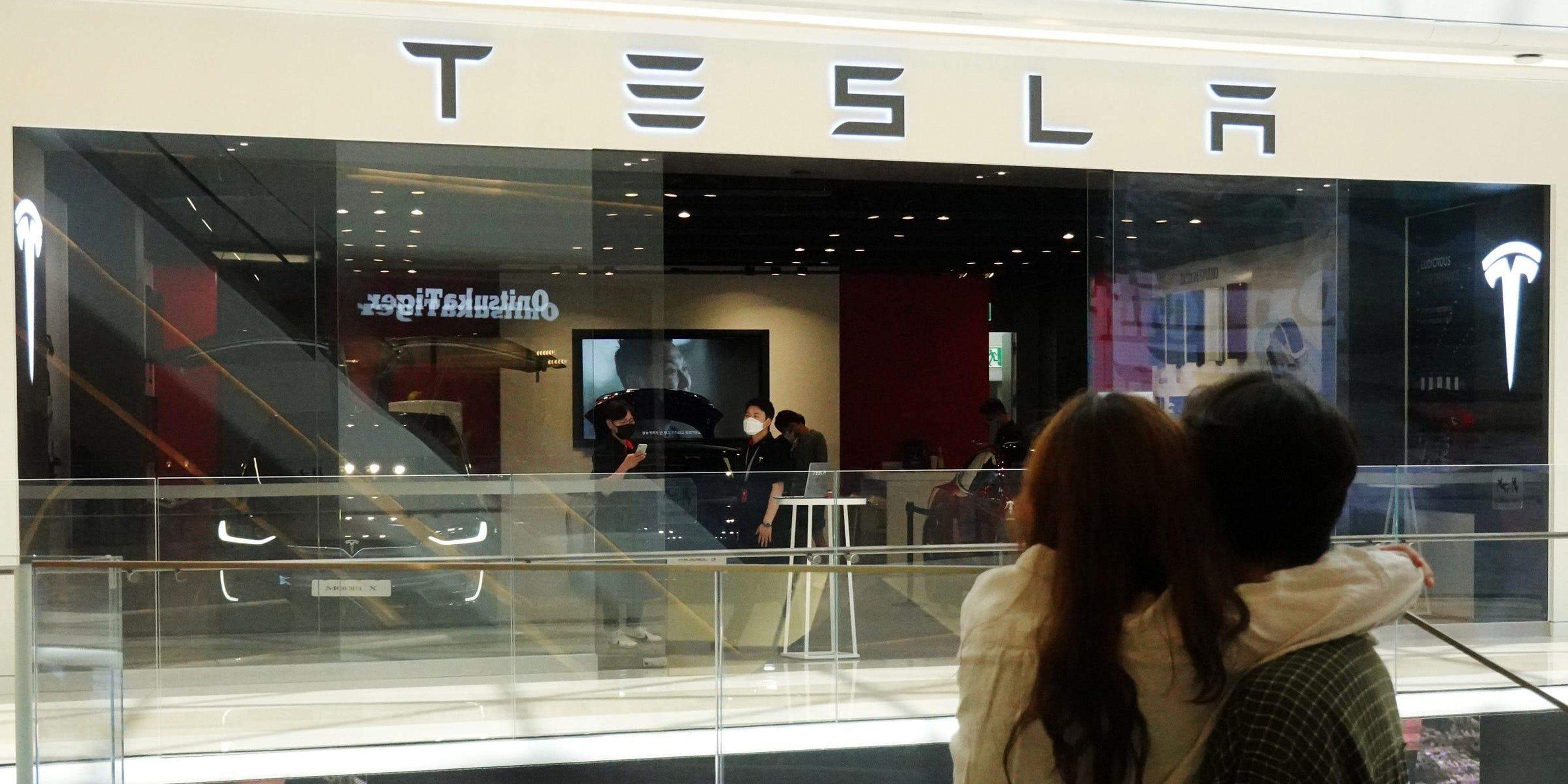 A couple looks at a Tesla dealership in Hanam, South Korea, July 6, 2020. REUTERS/Kim Hong-Ji