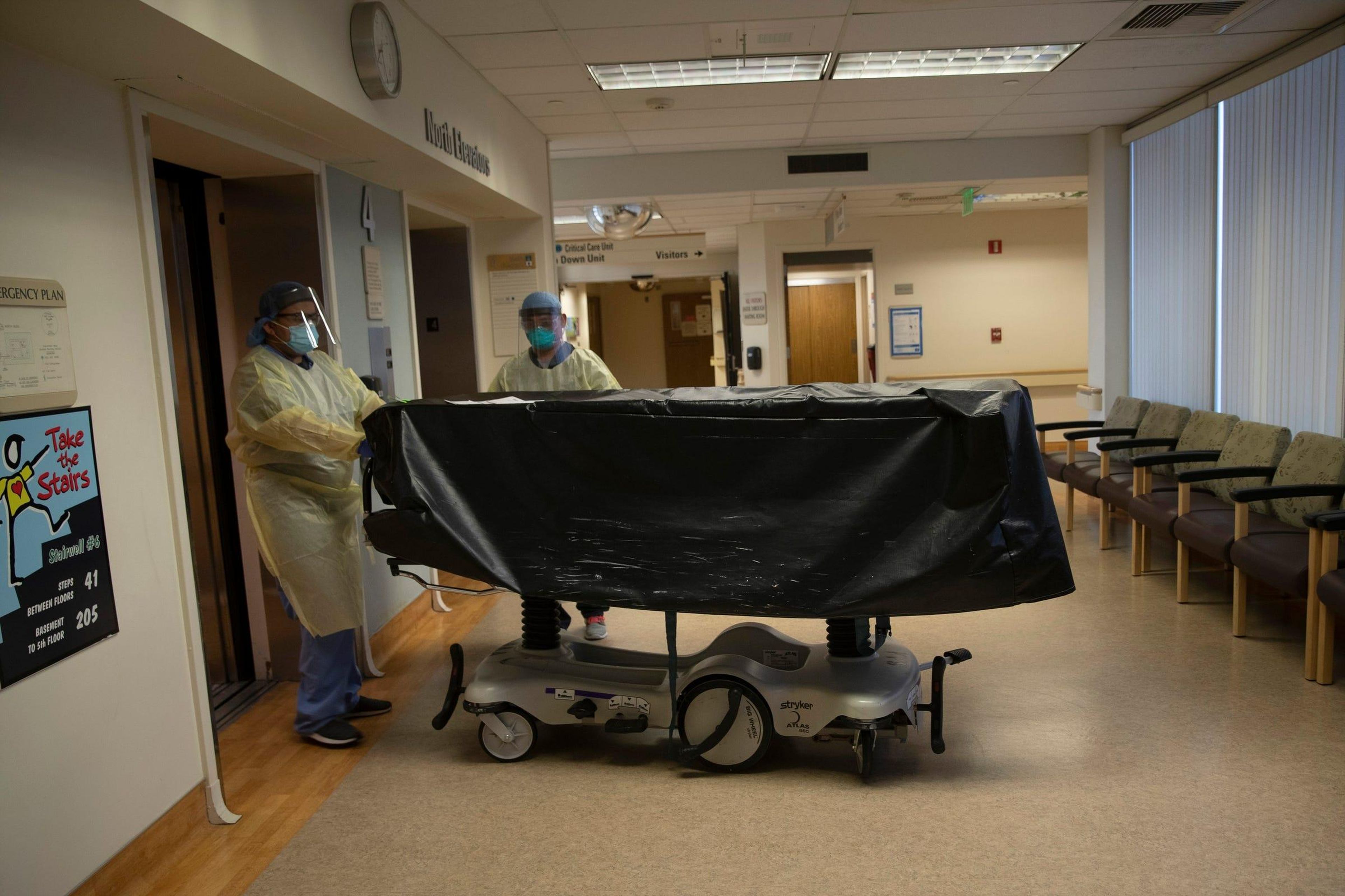 Los miembros del personal del hospital entran en el ascensor con el cuerpo de una víctima de COVID-19 en una camilla en el Centro Médico St. Jude en Fullerton, California.