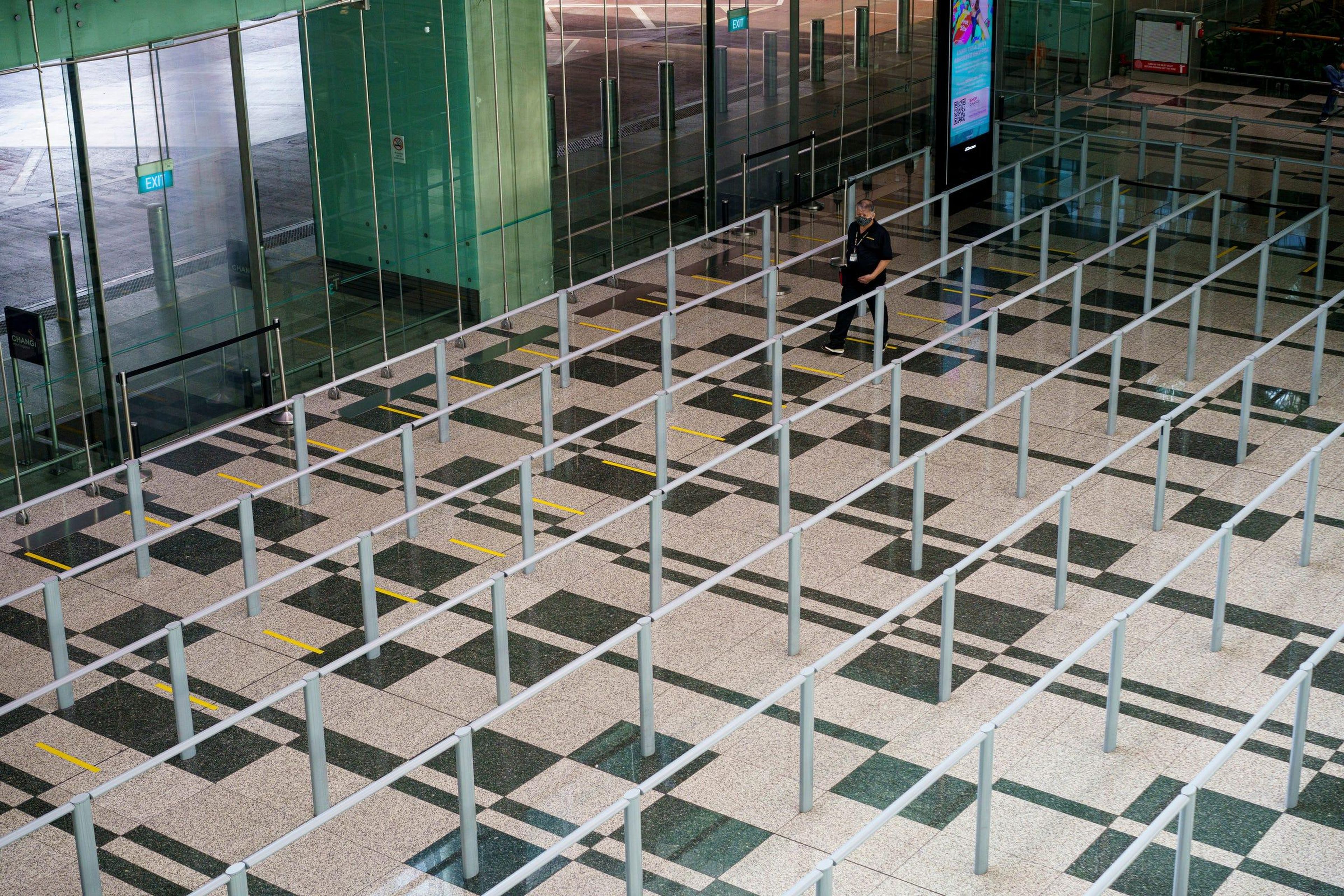 Un personal del aeropuerto camina a través de una sala de espera vacía para taxis en la sala de llegadas del aeropuerto de Changi.
