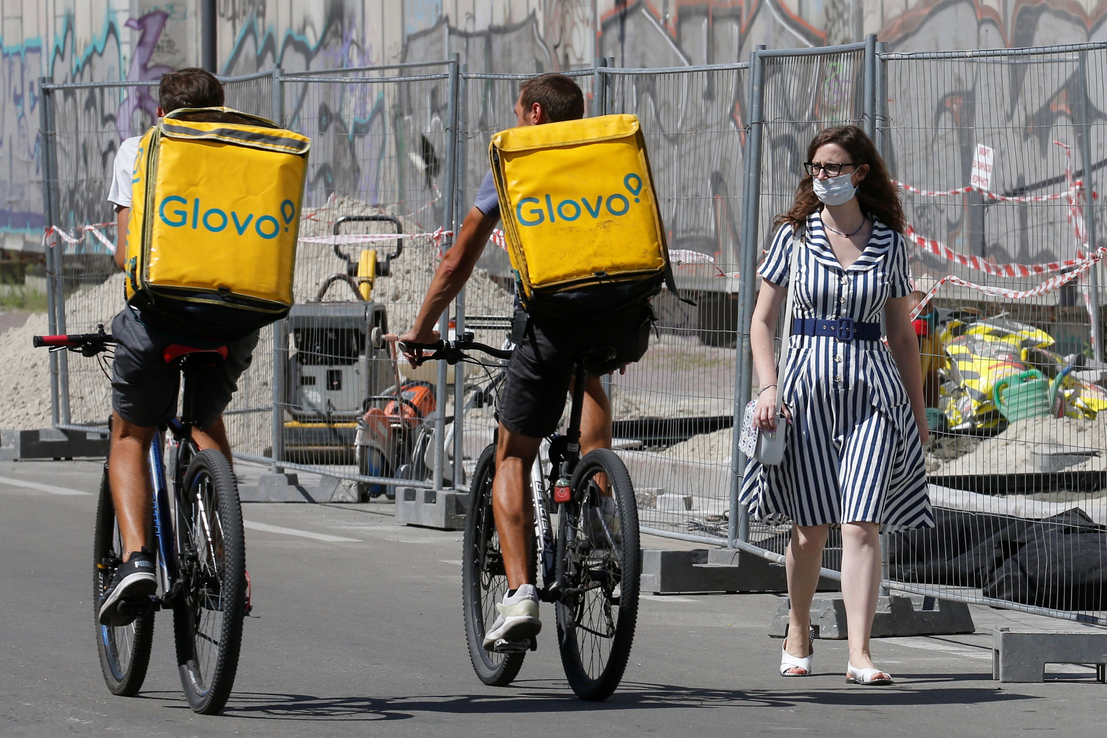 Dos repartidores de Glovo en bicicleta por Kiev, Ucrania.