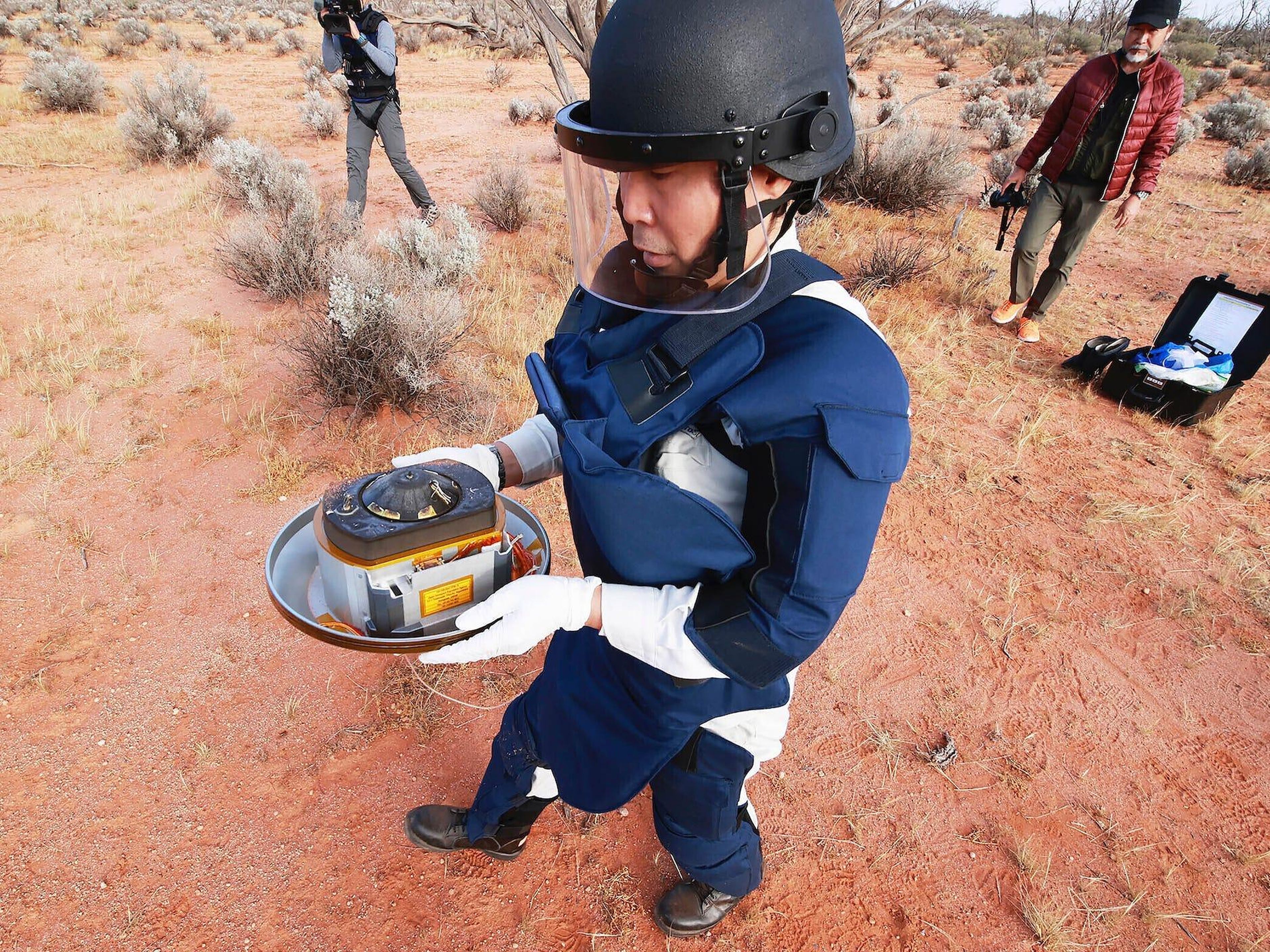 Un trabajador de JAXA recupera una cápsula lanzada por Hayabusa2 en Woomera, en el sur de Australia, el 6 de diciembre de 2020.