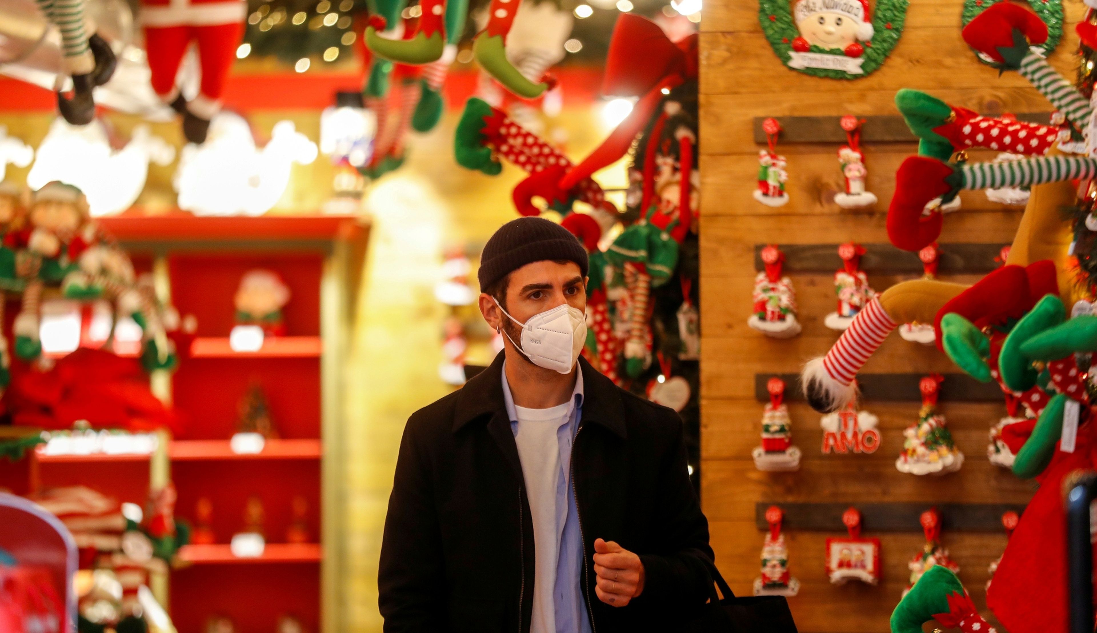Un hombre con mascarilla de compras en un mercado navideño en Roma