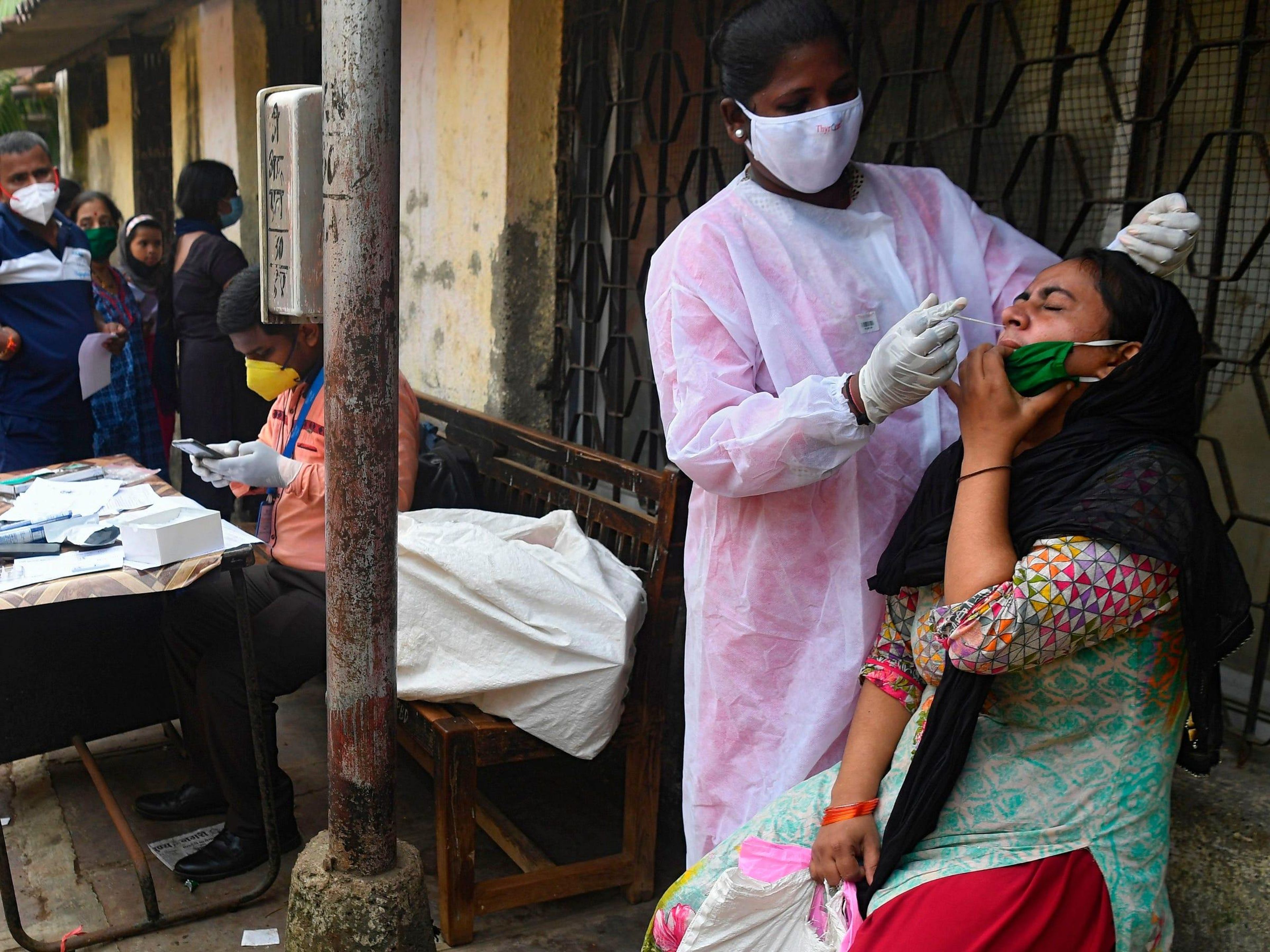 Sanitaria tomando una muestra de hisopo de una paciente durante una prueba de detección del COVID-19 en una clínica en los barrios marginales de Dharavi, en Mumbai.
