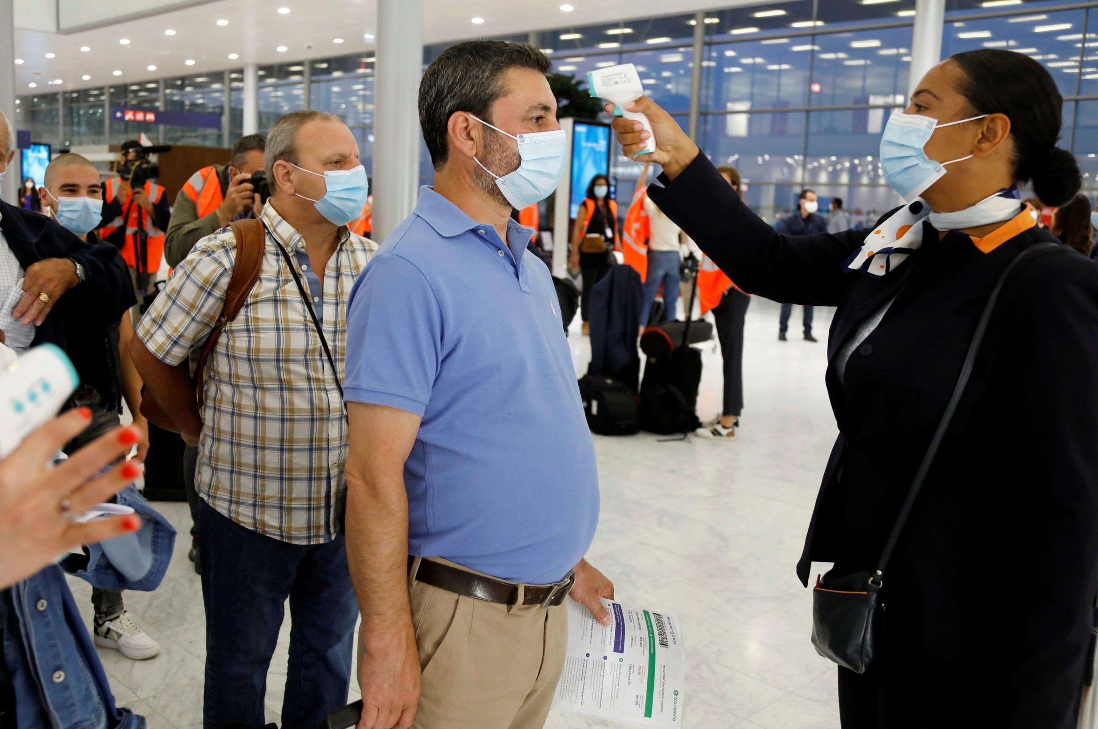 A un hombre le toman la temperatura antes de abordar un avión en el aeropuerto de París-Orly.