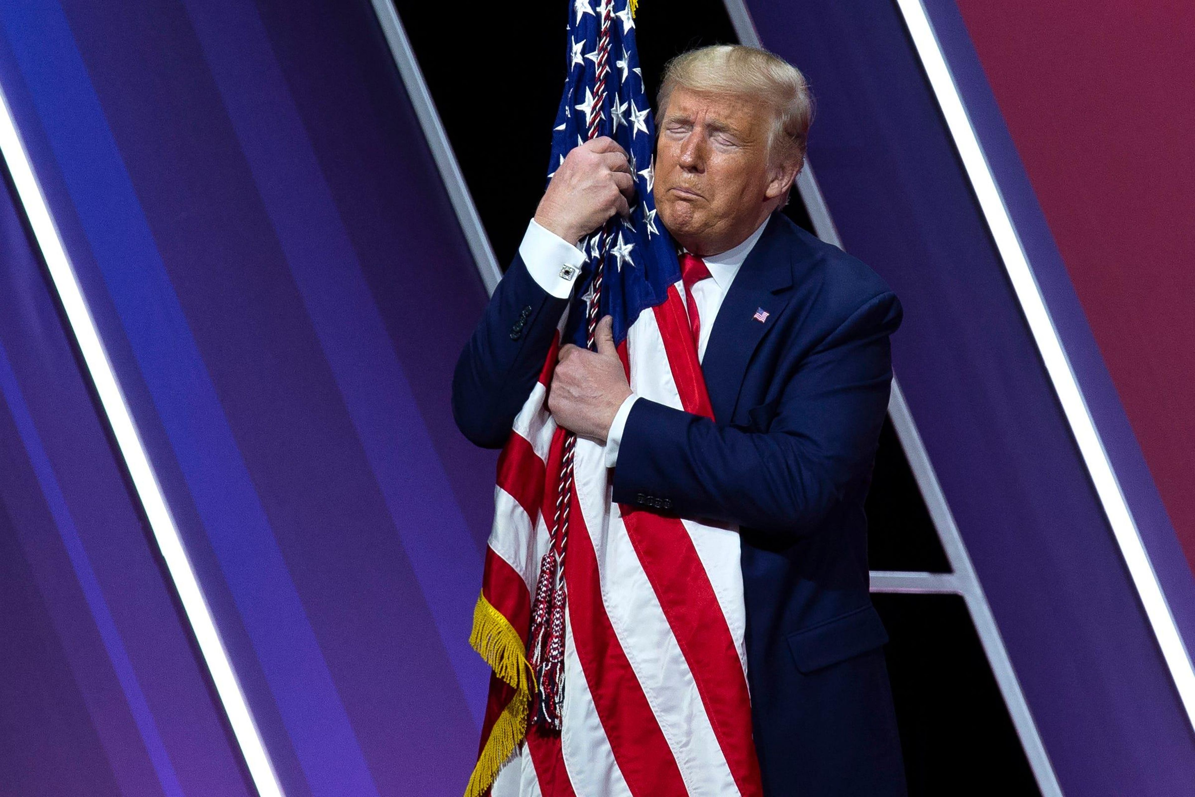 El presidente Donald Trump abraza y besa la bandera estadounidense.