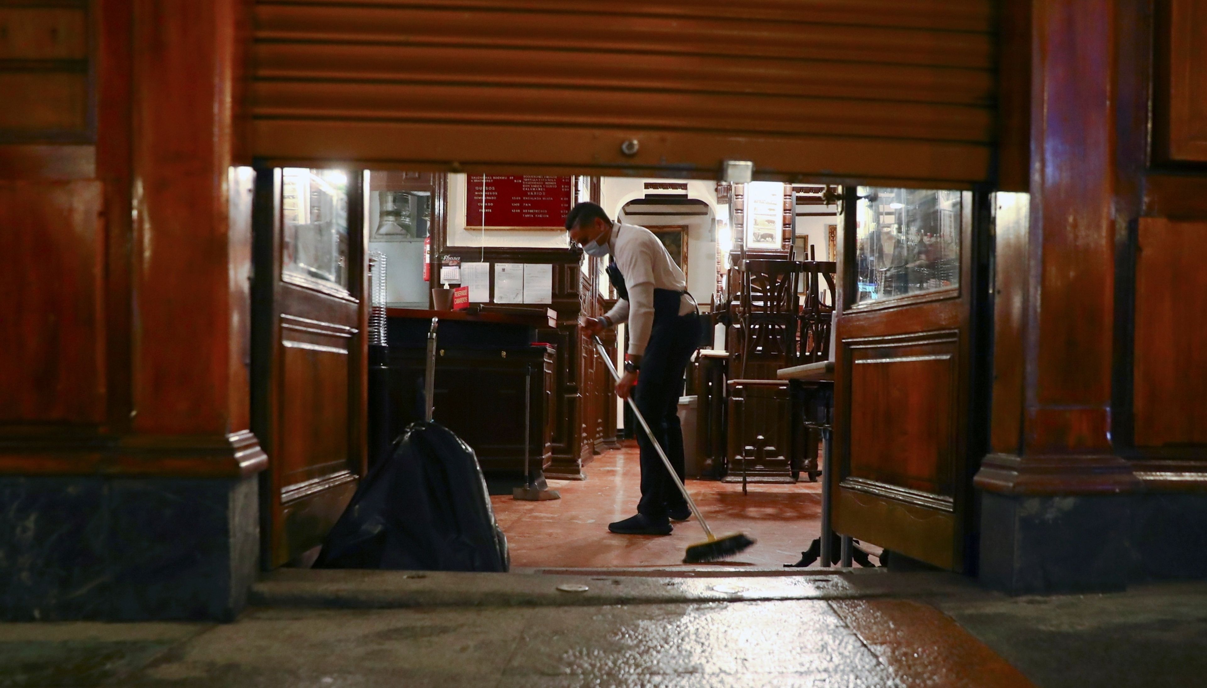 Un camarero friega el suelo de un bar de Madrid antes del toque de queda