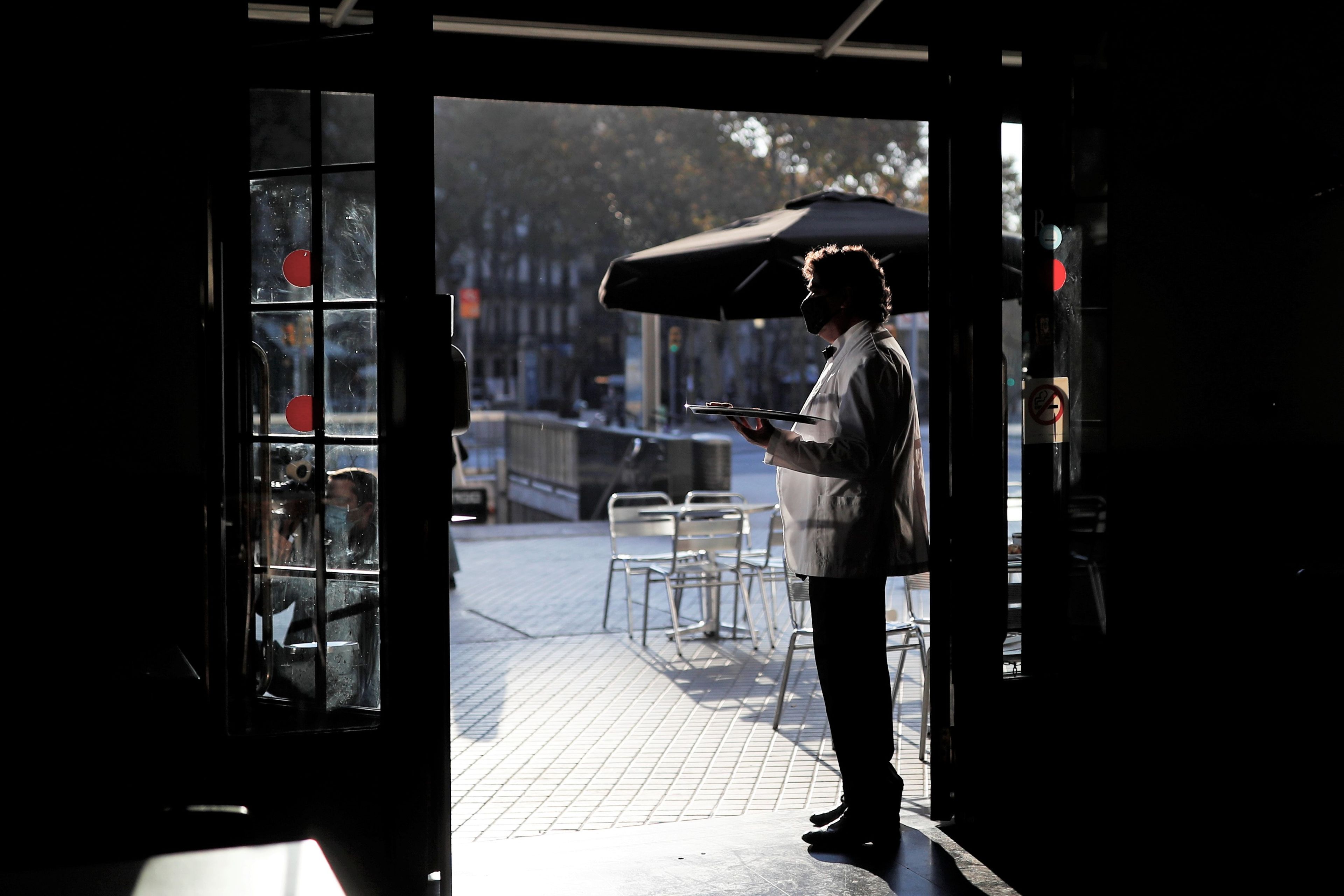 Un camarero en la puerta de un bar en Barcelona durante la pandemia de COVID-19.