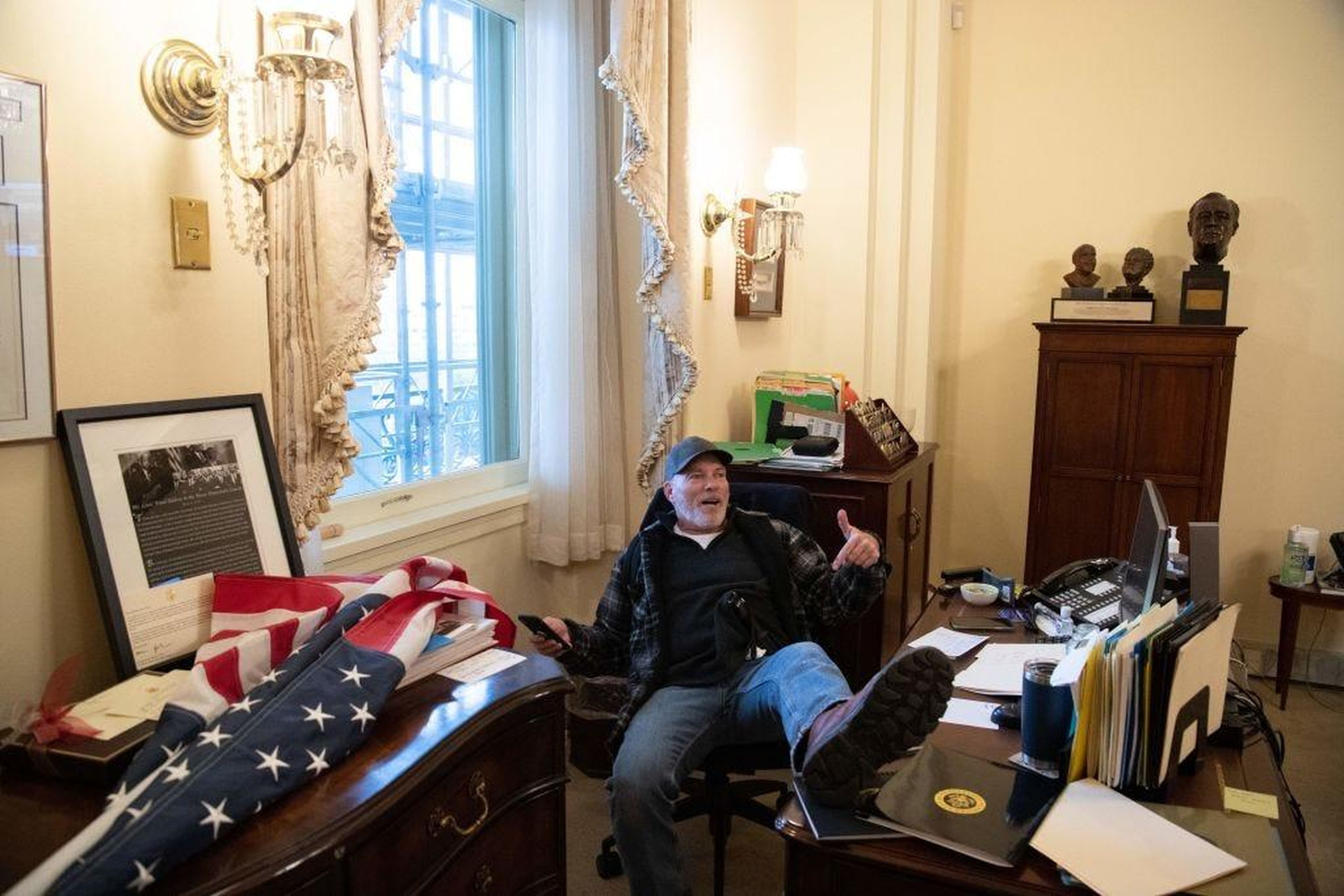 A supporter of US President Donald Trump sits inside the office of US Speaker of the House Nancy Pelosi.
