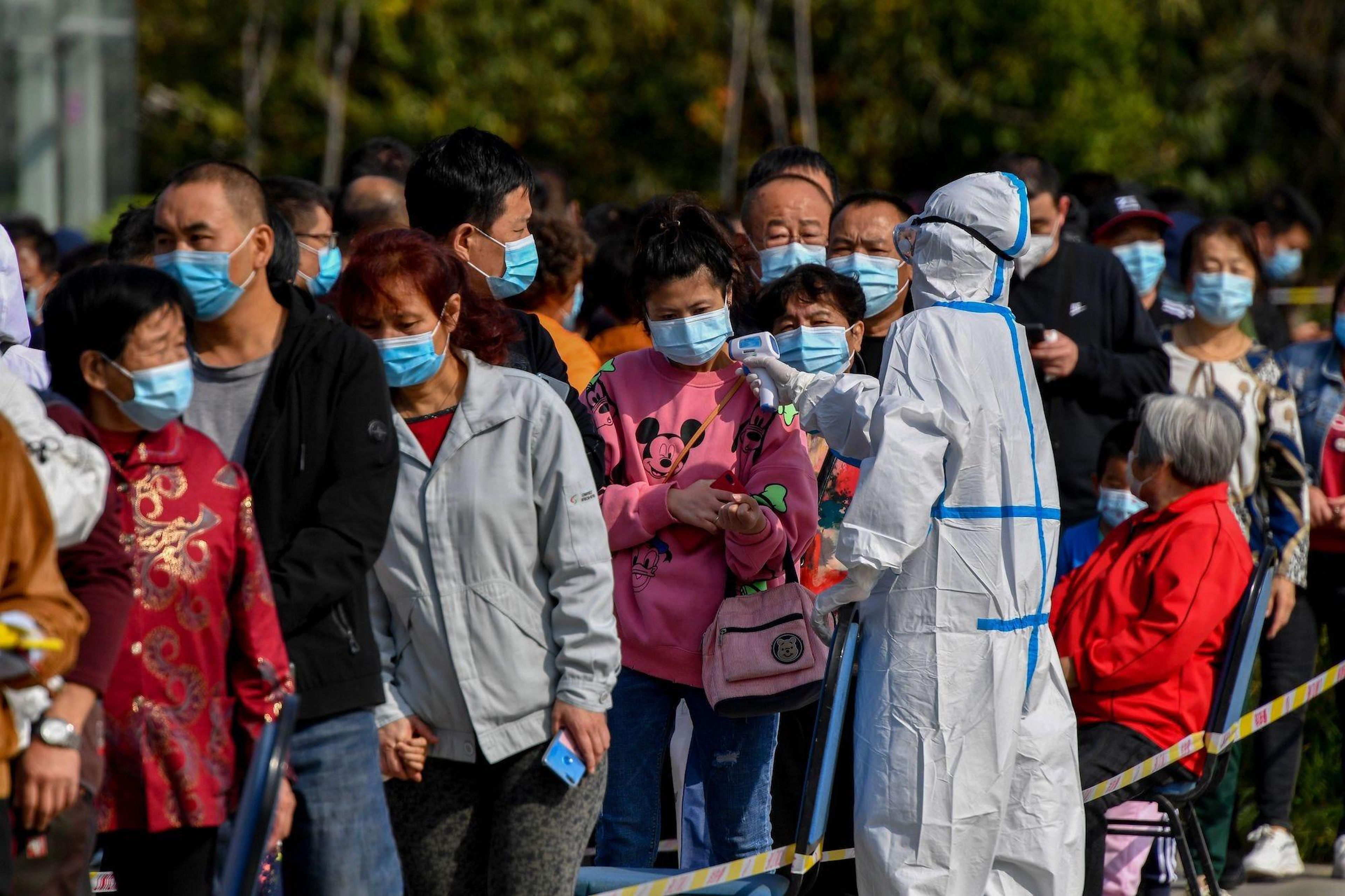Trabajadores de la salud en China, controlan la temperatura de quienes esperan las pruebas de COVID-19.
