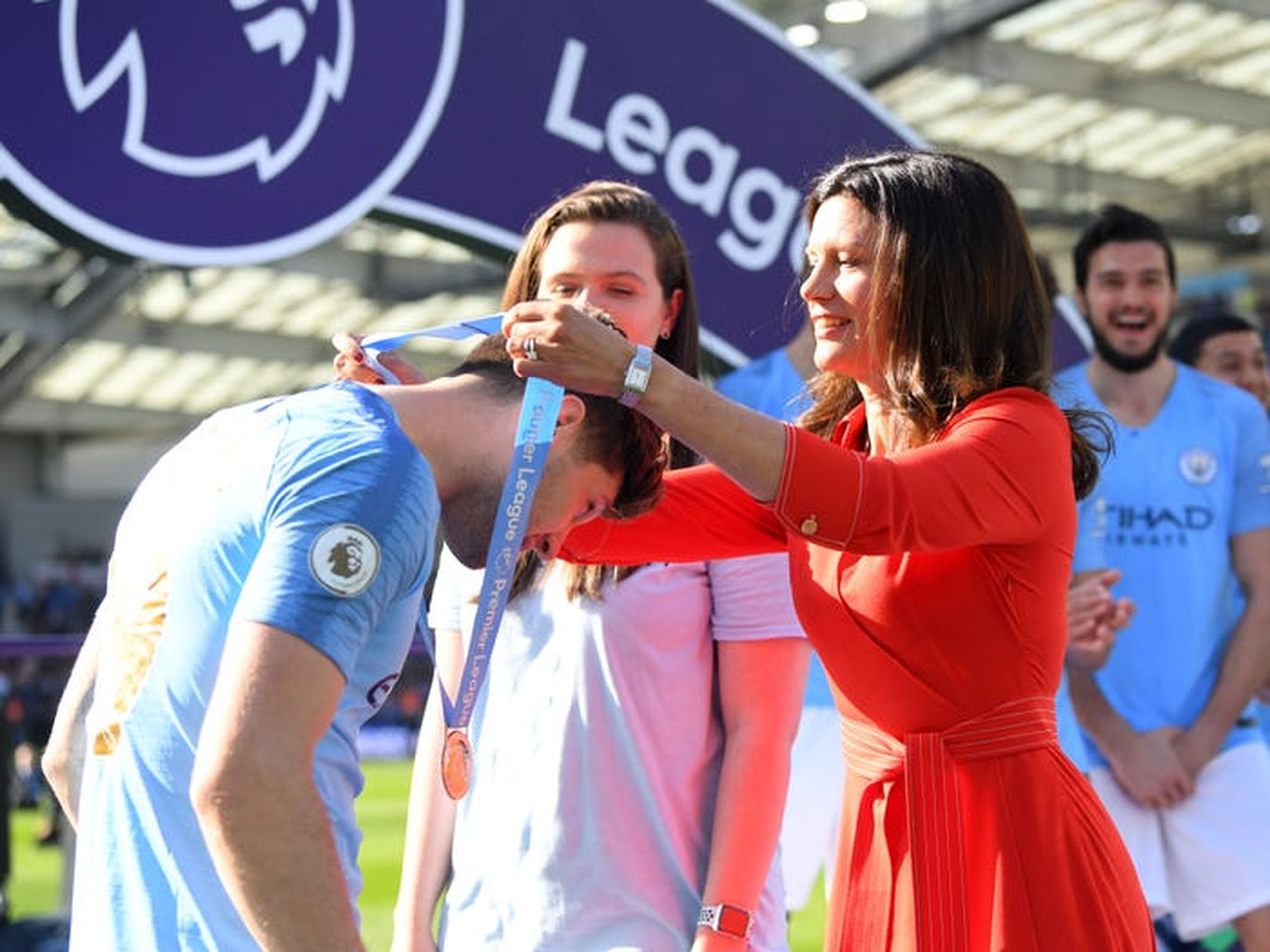 Claudia Anrey impone la medalla de ganador de la Premier League al defensor del Manchester City John Stones