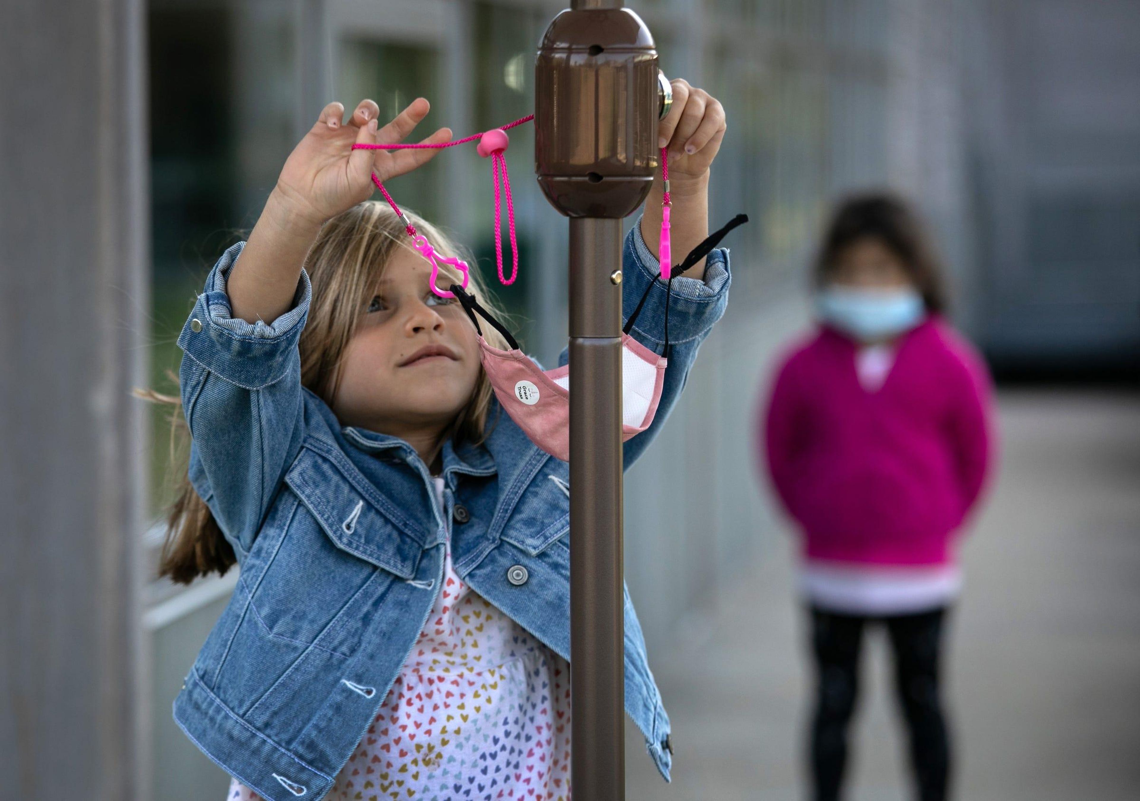 Una niña de 5 años, Grace Truax, se quita la máscara antes de posar para una foto durante el "día de la foto" en el Rogers International School, el 23 de septiembre de 2020 en Stamford, Connecticut, EEUU.
